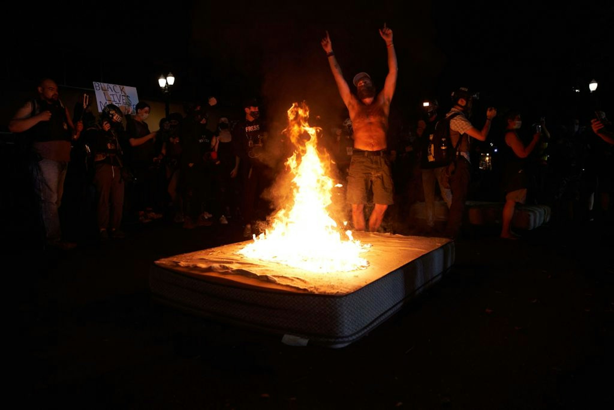 A protestor dances as mattresses are set on fire in front of the North Precinct Police building in Portland, Oregon on September 6, 2020.