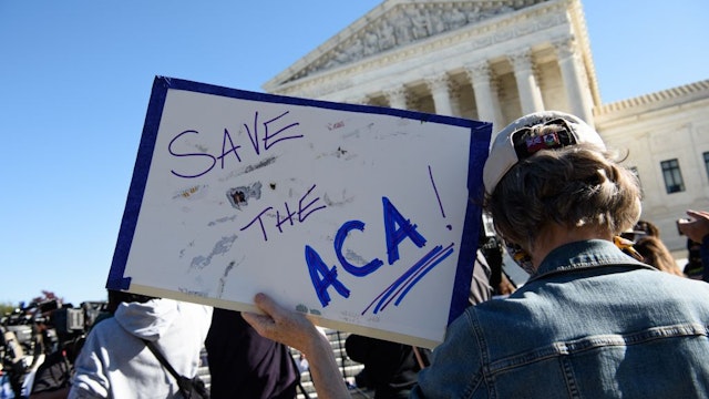 A demonstrator holds a sign in front of the US Supreme Court in Washington, DC, on November 10, 2020, as the high court opened arguments in the long-brewing case over the constitutionality of the 2010 Affordable Care Act, under which then-president Barack Obama's government sought to extend health insurance to people who could not afford it. - President Donald Trump's outgoing administration took aim in the US Supreme Court Tuesday at razing the "Obamacare" health program his predecessor built, a move which could cancel the health insurance of millions in the middle of the Covid-19 pandemic. (Photo by NICHOLAS KAMM / AFP) (Photo by NICHOLAS KAMM/AFP via Getty Images)