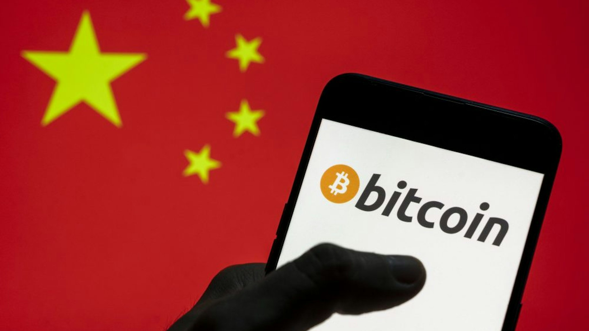 CHINA - 2021/03/28: In this photo illustration the Cryptocurrency electronic cash Bitcoin logo seen on an Android mobile device with People's Republic of China flag in the background.