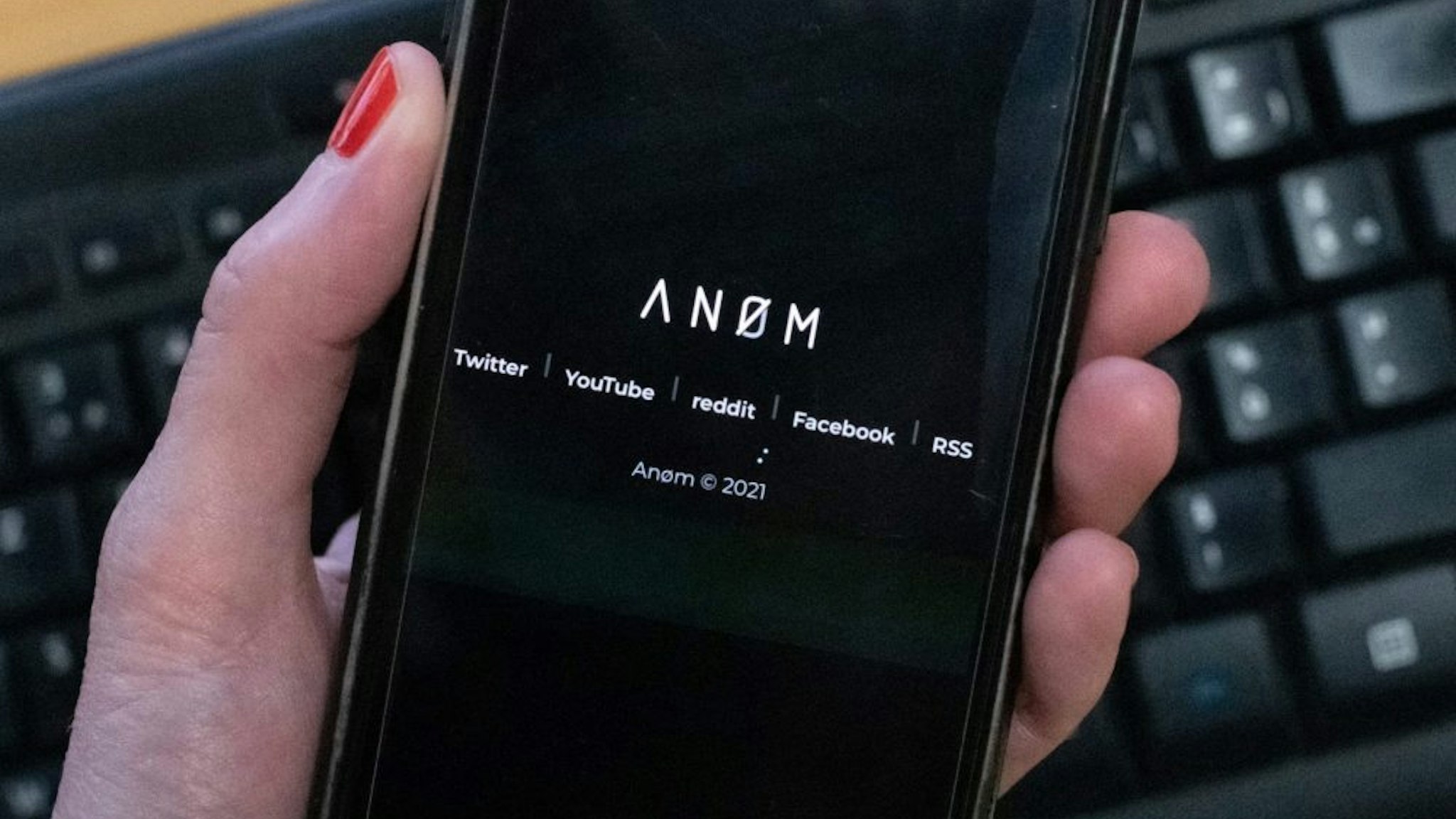 An illustration picture shows the ANoM logo displayed on the screen of an smartphone on june 8, 2021 in Paris. - Some 250 people were arrested in Sweden and Finland in the global sting on organised crime, authorities said on June 8, 2021, using phones planted by the US FBI, law enforcement officers were able to read the messages of global underworld figures in around 100 countries as they plotted drug deals, arms transfers and gangland hits on the compromised ANOM devices.