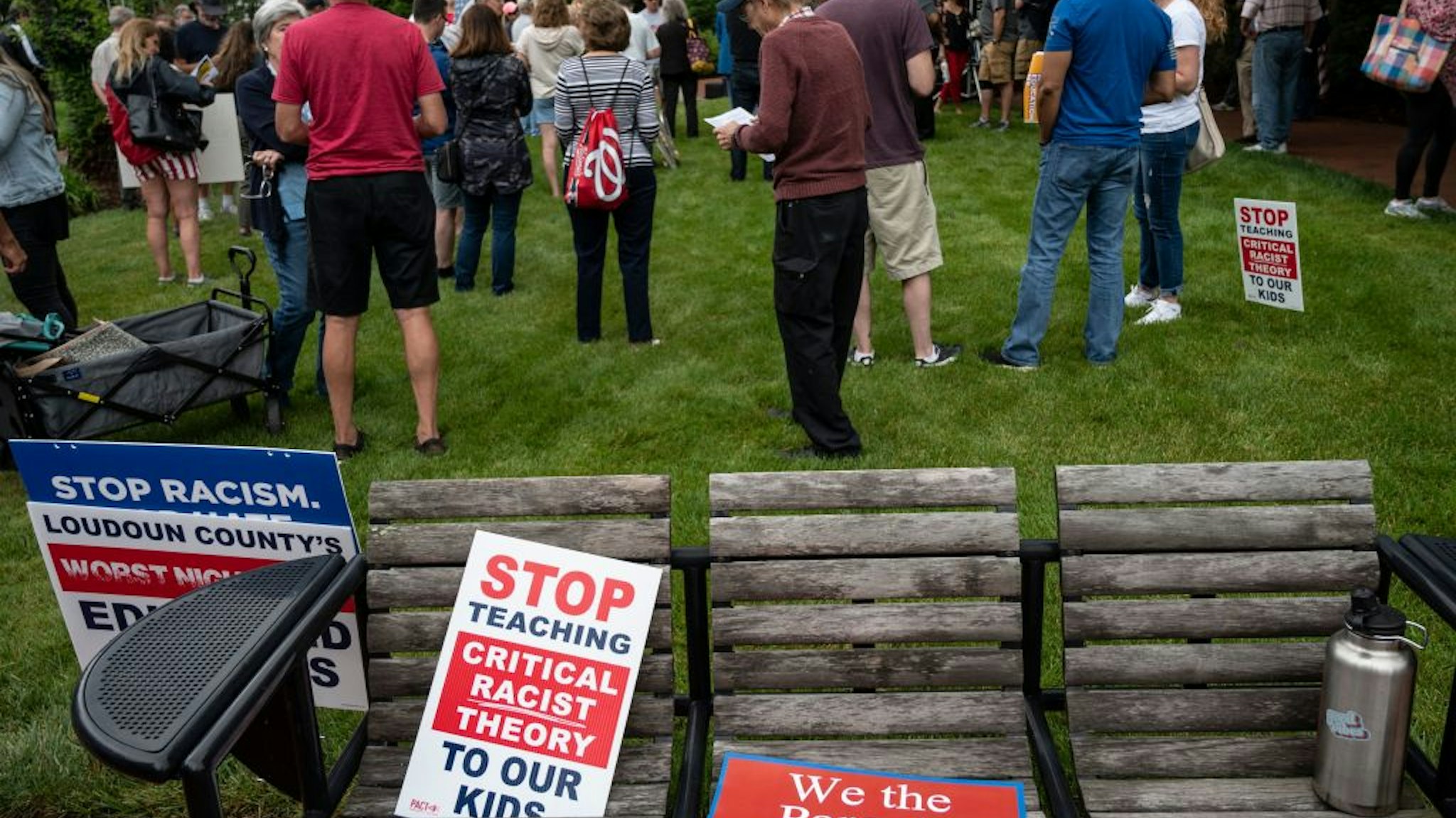 Signs are seen on a bench during a rally against "critical race theory" (CRT) being taught in schools at the Loudoun County Government center in Leesburg, Virginia on June 12, 2021. - "Are you ready to take back our schools?" Republican activist Patti Menders shouted at a rally opposing anti-racism teaching that critics like her say trains white children to see themselves as "oppressors." "Yes!", answered in unison the hundreds of demonstrators gathered this weekend near Washington to fight against "critical race theory," the latest battleground of America's ongoing culture wars. The term "critical race theory" defines a strand of thought that appeared in American law schools in the late 1970s and which looks at racism as a system, enabled by laws and institutions, rather than at the level of individual prejudices. But critics use it as a catch-all phrase that attacks teachers' efforts to confront dark episodes in American history, including slavery and segregation, as well as to tackle racist stereotypes. (Photo by ANDREW CABALLERO-REYNOLDS / AFP) (Photo by ANDREW CABALLERO-REYNOLDS/AFP via Getty Images)