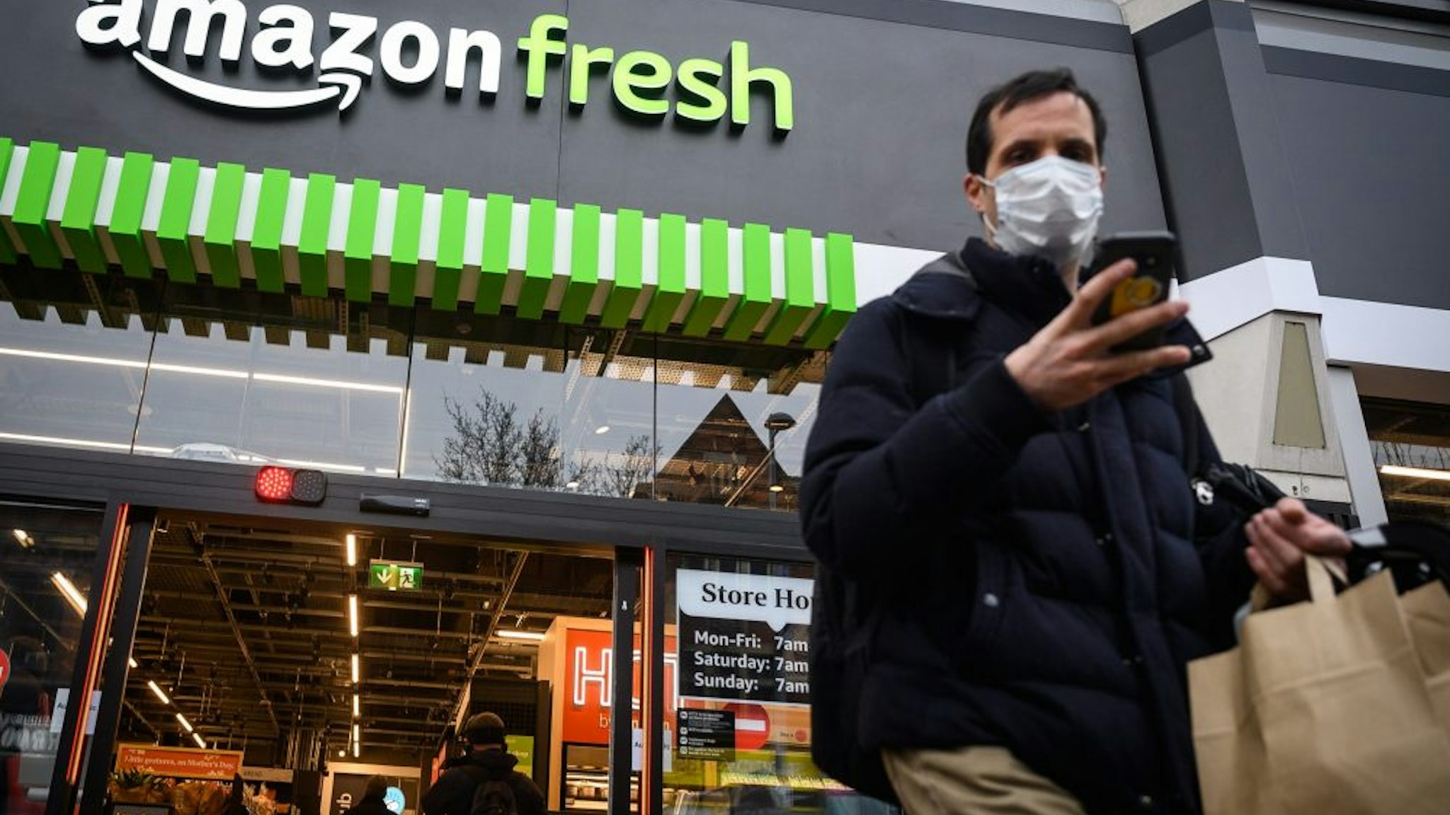 LONDON, ENGLAND - MARCH 04: Customers carry their purchases as they leave the UK's first branch of Amazon Fresh, on March 04, 2021, in the Ealing area of London, England. Shoppers at the Amazon Fresh store, which stocks hundreds of Amazon-owned products and third-party items, check in with a smartphone app upon entry and are automatically billed when they exit, without needing to scan individual items. The location is Amazon's first "just walk out" shop outside the United States.