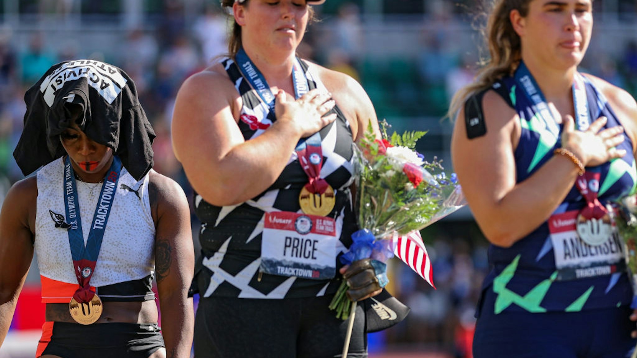 Gwendolyn Berry (L), third place, turns away from U.S. flag during the U.S. National Anthem as DeAnna Price (C), first place, and Brooke Andersen, second place, also stand on the podium after the Women's Hammer Throw final on day nine of the 2020 U.S. Olympic Track & Field Team Trials at Hayward Field on June 26, 2021 in Eugene, Oregon.