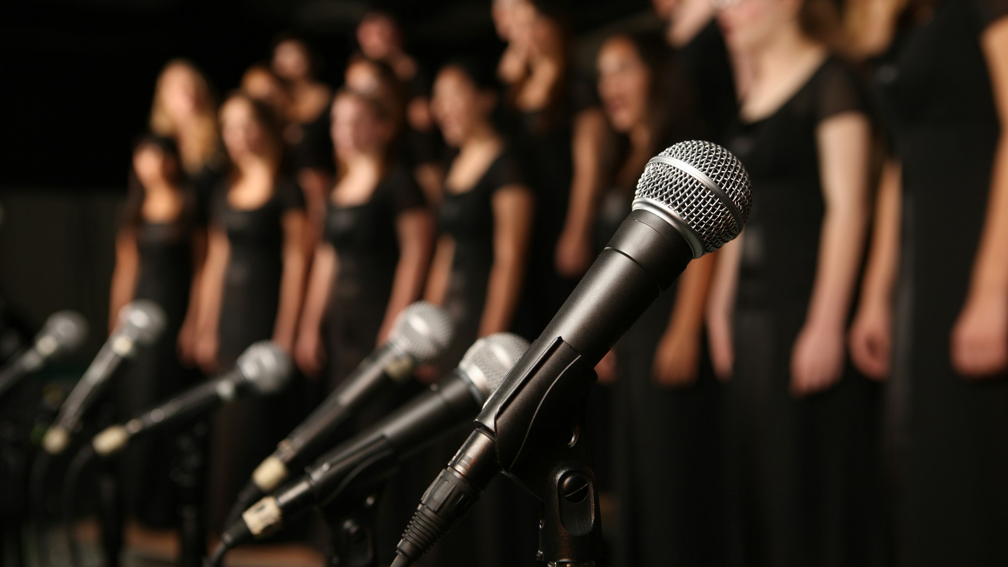 Shot of microphones with choir in the background - stock photo