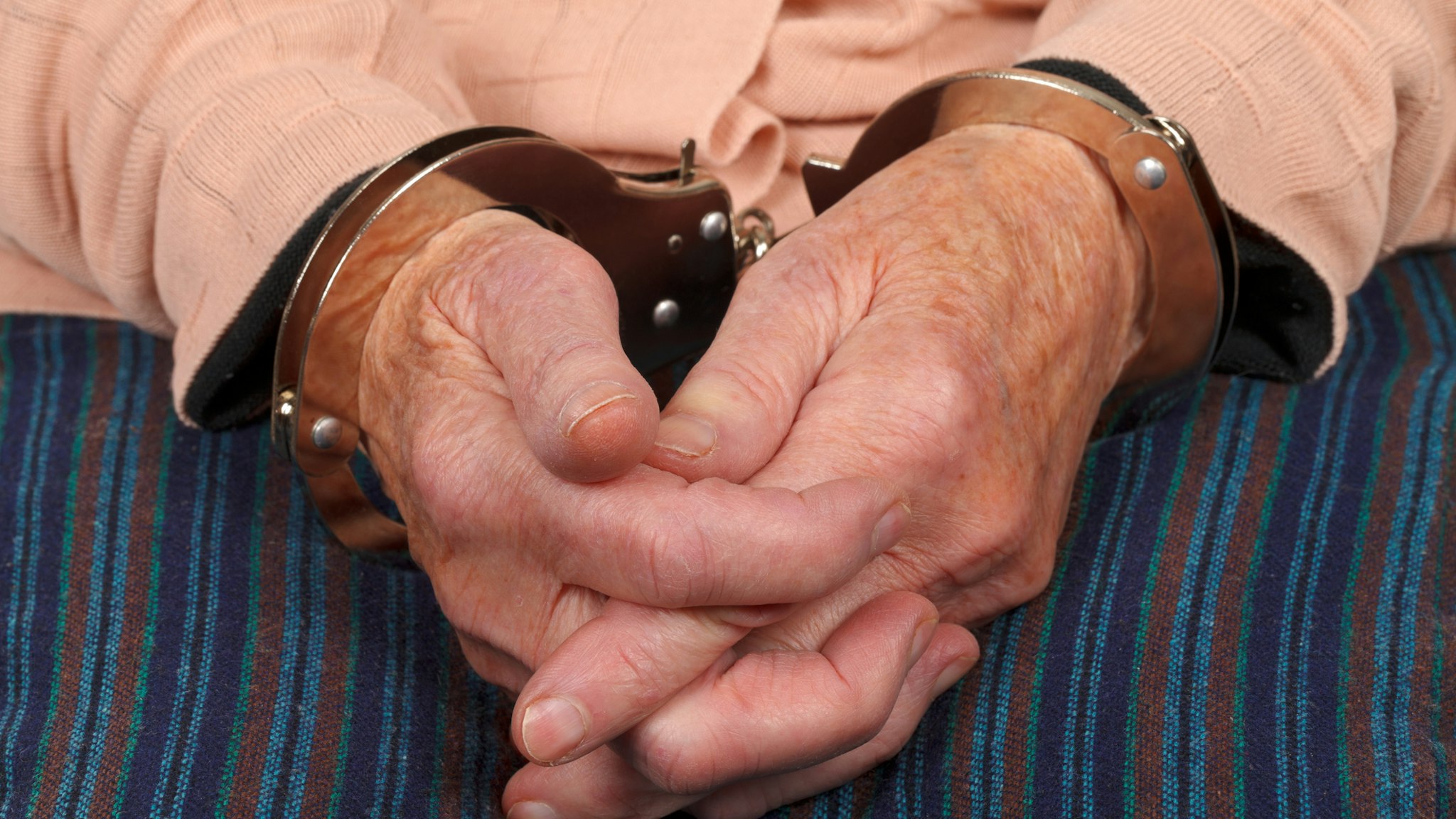 Handcuffed elderly woman - stock photo