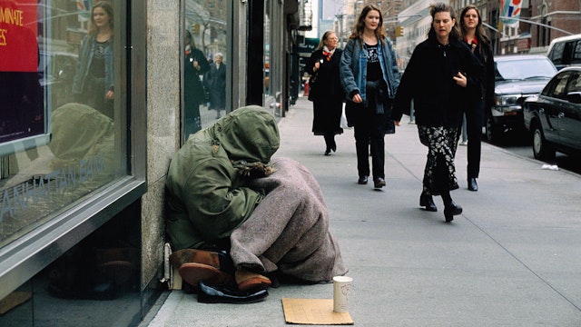 A group of women walk past a homeless woman begging for money along a city sidewalk. (Photo by © Viviane Moos/CORBIS/Corbis via Getty Images)