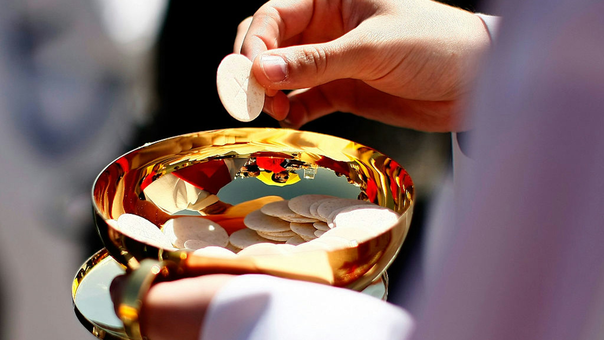 WASHINGTON - APRIL 17: A priest holds a Holy Communion wafer as Pope Benedict XVI celebrates Mass at Nationals Park April 17, 2008 in Washington, DC. Today is Pope Benedict XVI's third day of his visit to the United States. (Photo by Win McNamee/Getty Images)