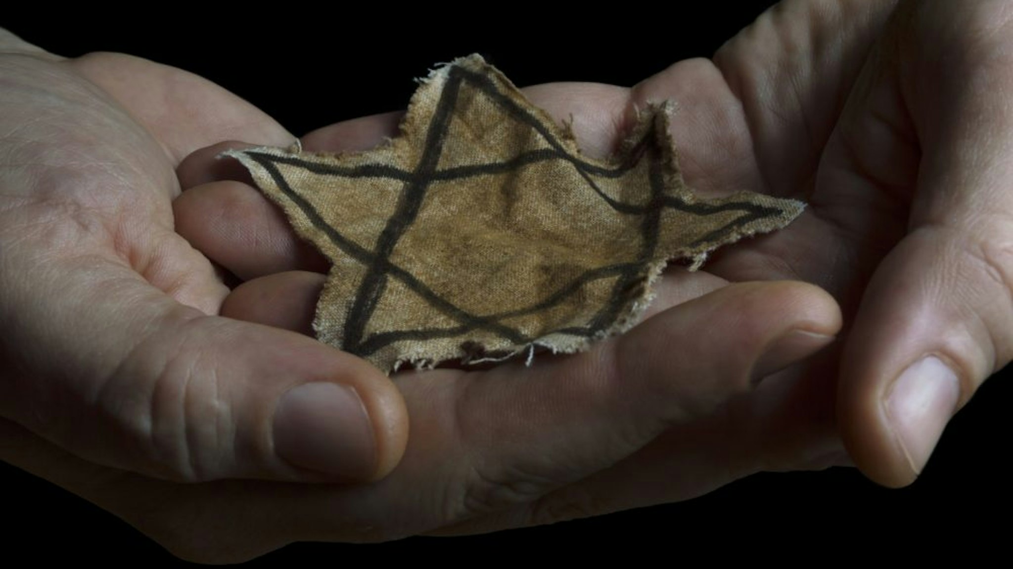 Closeup of a ragged Jewish badge in the hands of a man