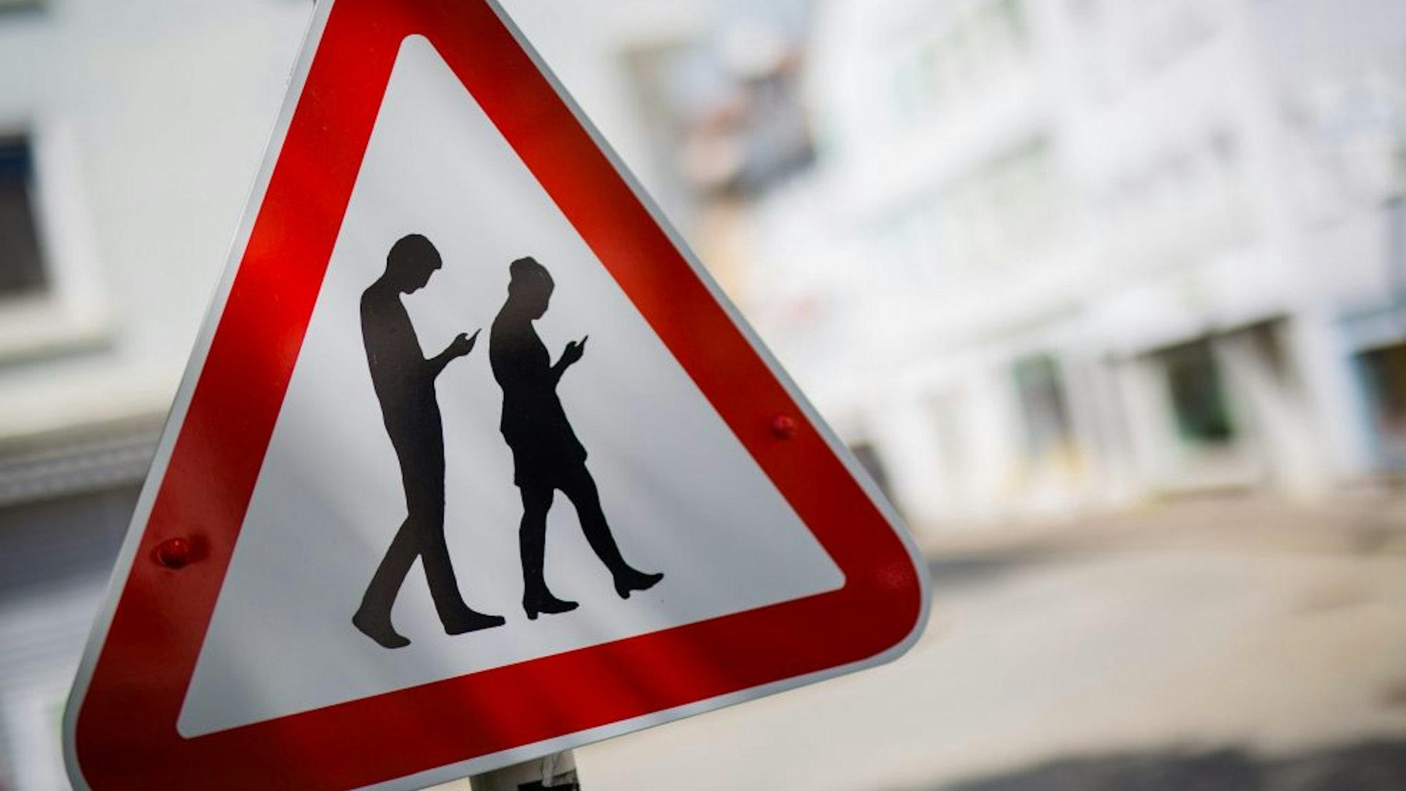 TOPSHOT - Picture taken on April 25, 2018 shows a modified caution sign warning against so-called "smombies", people watching their smartphones, in a street close to a school in Reutlingen, southern Germany. - The word "Smombie", a composition of "smartphone" and "zombie", describes people staring at their smartphones while walking around, even it it puts themselves and others in danger.