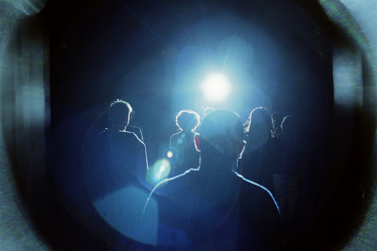 Crowd of people walking towards bright light, rear view