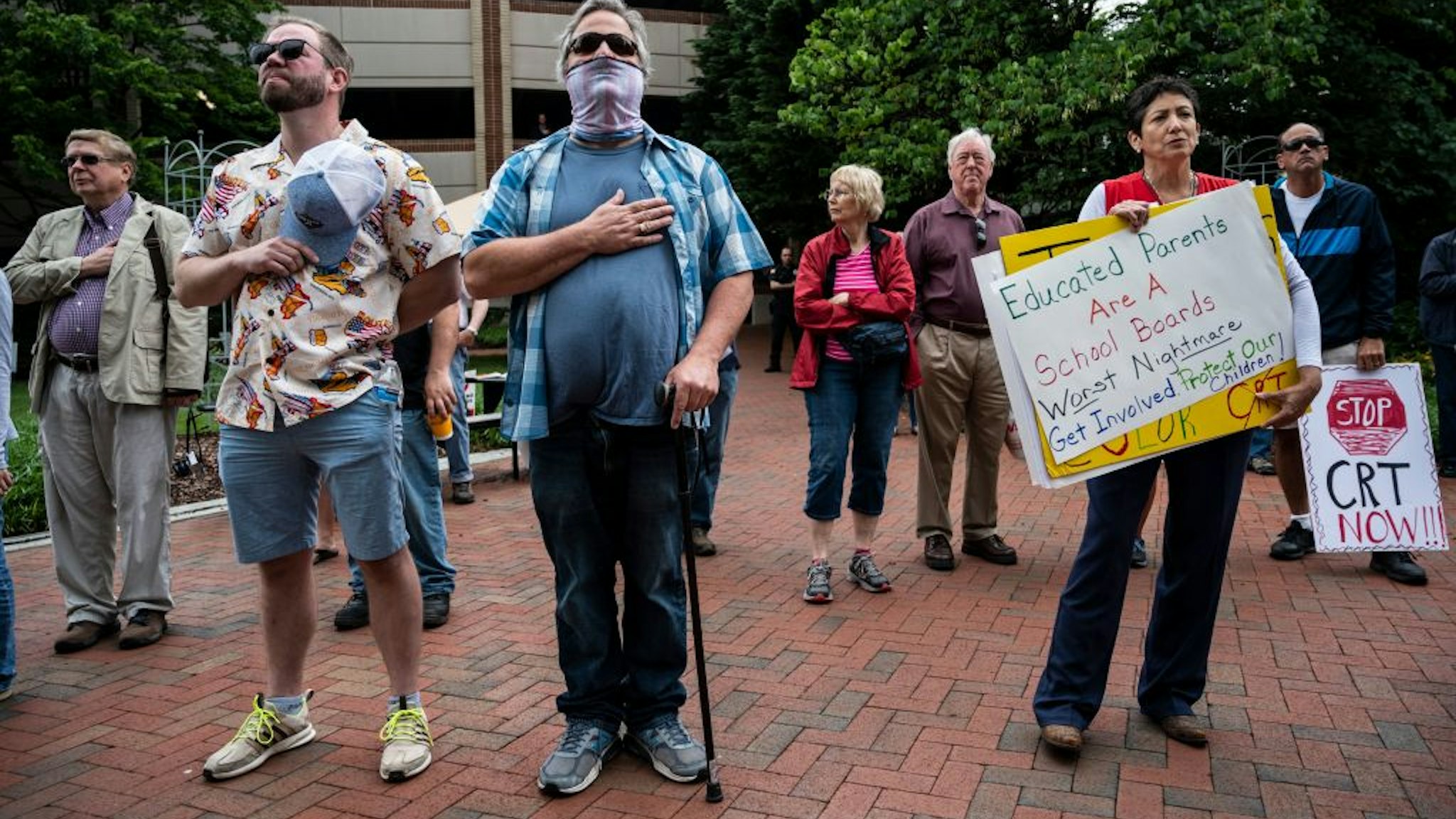 People hold up signs during a rally against "critical race theory" (CRT) being taught in schools at the Loudoun County Government center in Leesburg, Virginia on June 12, 2021. - "Are you ready to take back our schools?" Republican activist Patti Menders shouted at a rally opposing anti-racism teaching that critics like her say trains white children to see themselves as "oppressors." "Yes!", answered in unison the hundreds of demonstrators gathered this weekend near Washington to fight against "critical race theory," the latest battleground of America's ongoing culture wars. The term "critical race theory" defines a strand of thought that appeared in American law schools in the late 1970s and which looks at racism as a system, enabled by laws and institutions, rather than at the level of individual prejudices. But critics use it as a catch-all phrase that attacks teachers' efforts to confront dark episodes in American history, including slavery and segregation, as well as to tackle racist stereotypes.
