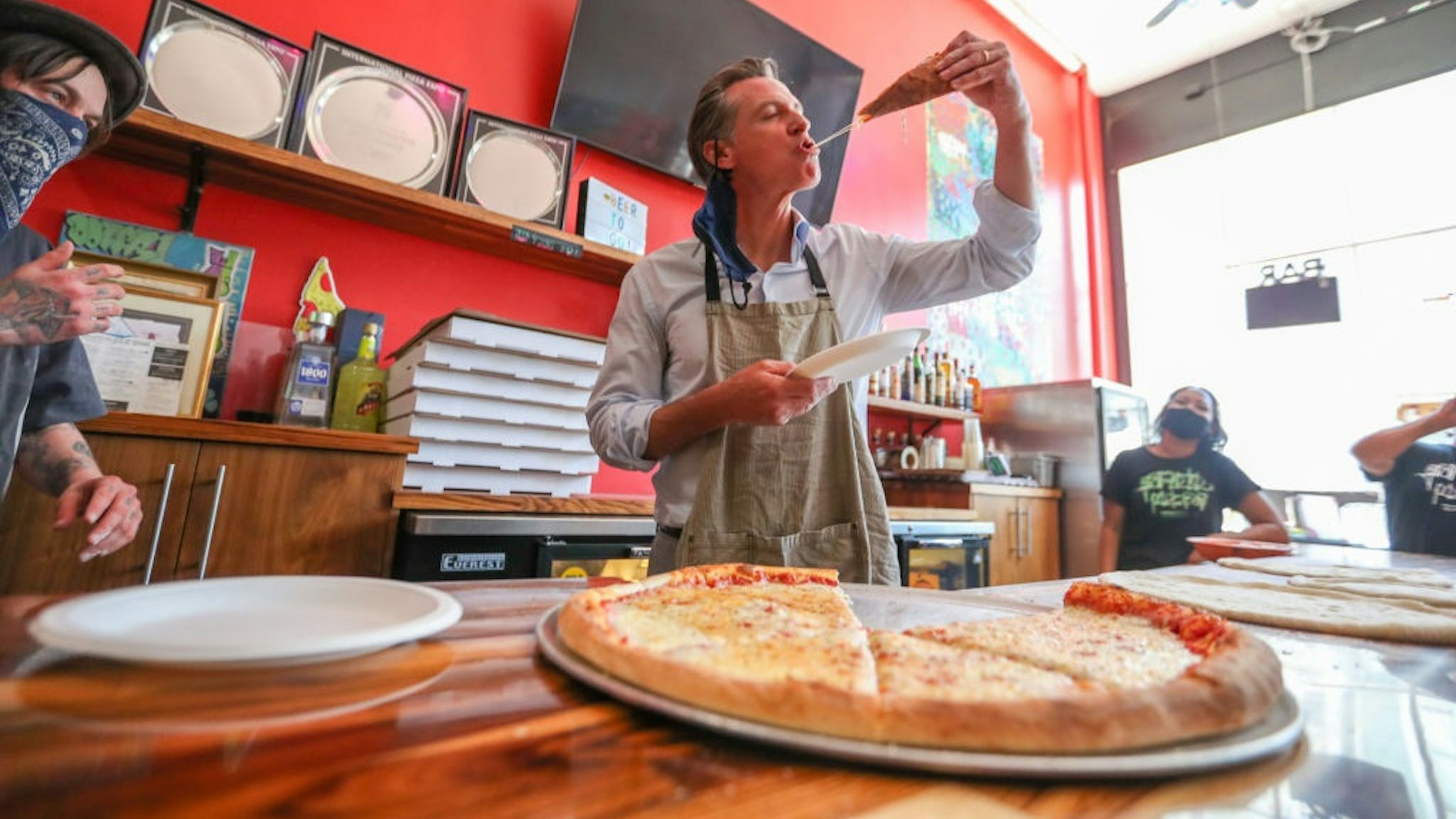 OAKLAND, CA - JUNE 17: Graffiti Pizza executive chef Matt Molina, left, looks on as California Governor Gavin Newsom tries a slice of pizza during a visit to Graffiti Pizza in Oakland, Calif., on Thursday, June 17, 2021.