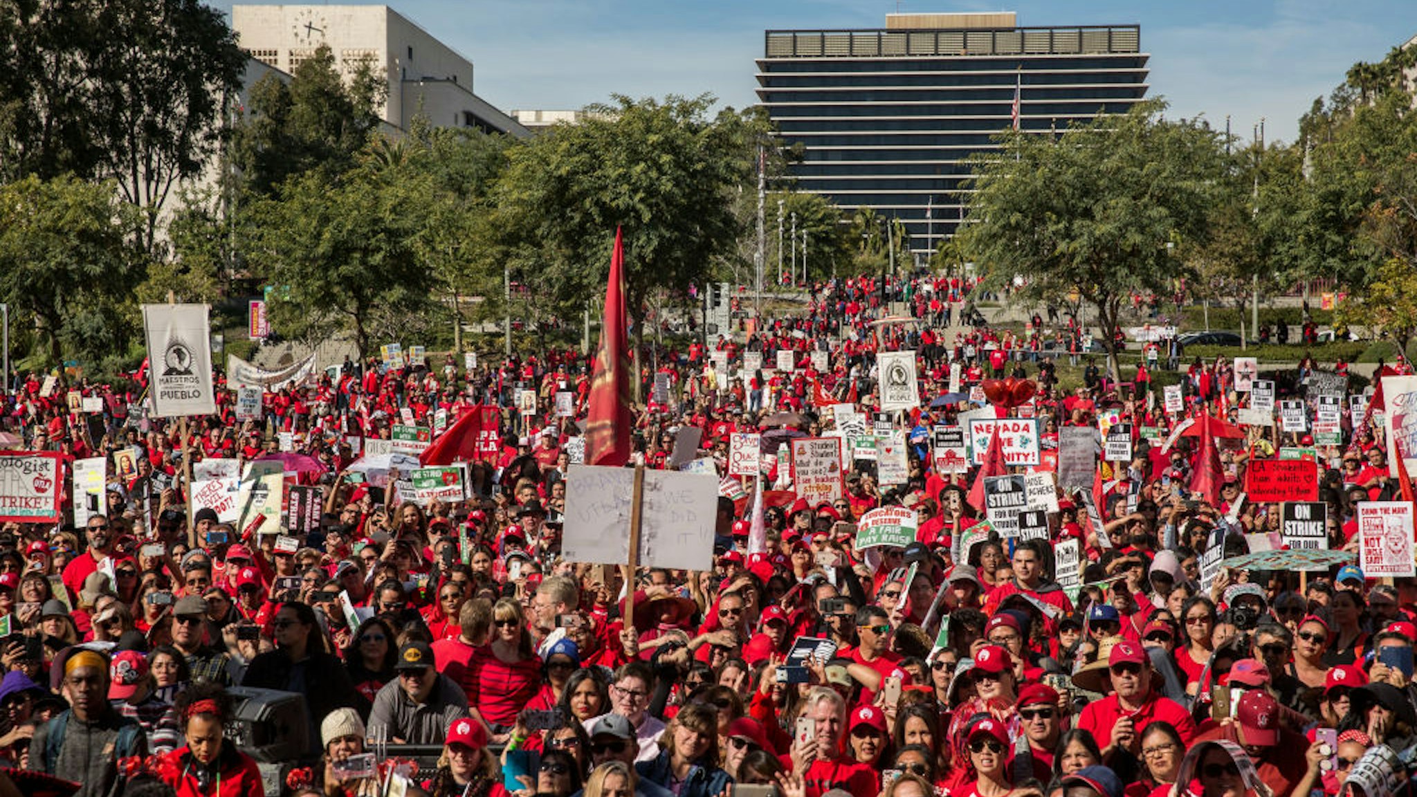 LOS ANGELES, CA - JANUARY 22: Educators, parents, students, and supporters of the Los Angeles teachers strike wave and cheer in Grand Park on January 22, 2019 in downtown Los Angeles, California.Thousands of striking teachers cheered for victory at the rally after it was announced that a tentative deal between the United Teachers of Los Angeles union and the Los Angeles Unified School District heavily favored educators' demands including a cap on rising class sizes, funding for school nurses, and a significant pay increase.
