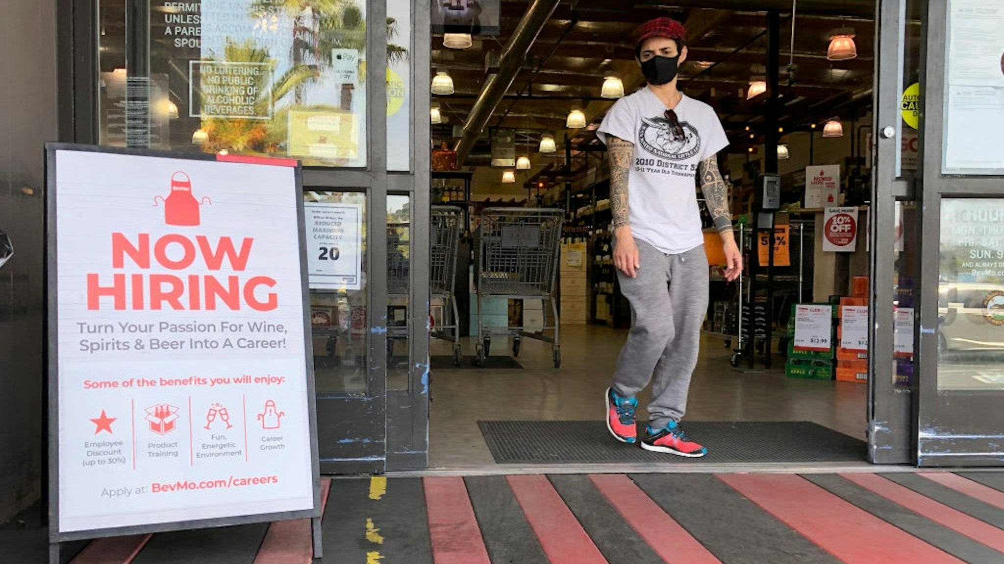 LARKSPUR, CALIFORNIA - APRIL 02: A customer walks by a now hiring sign at a BevMo store on April 02, 2021 in Larkspur, California.