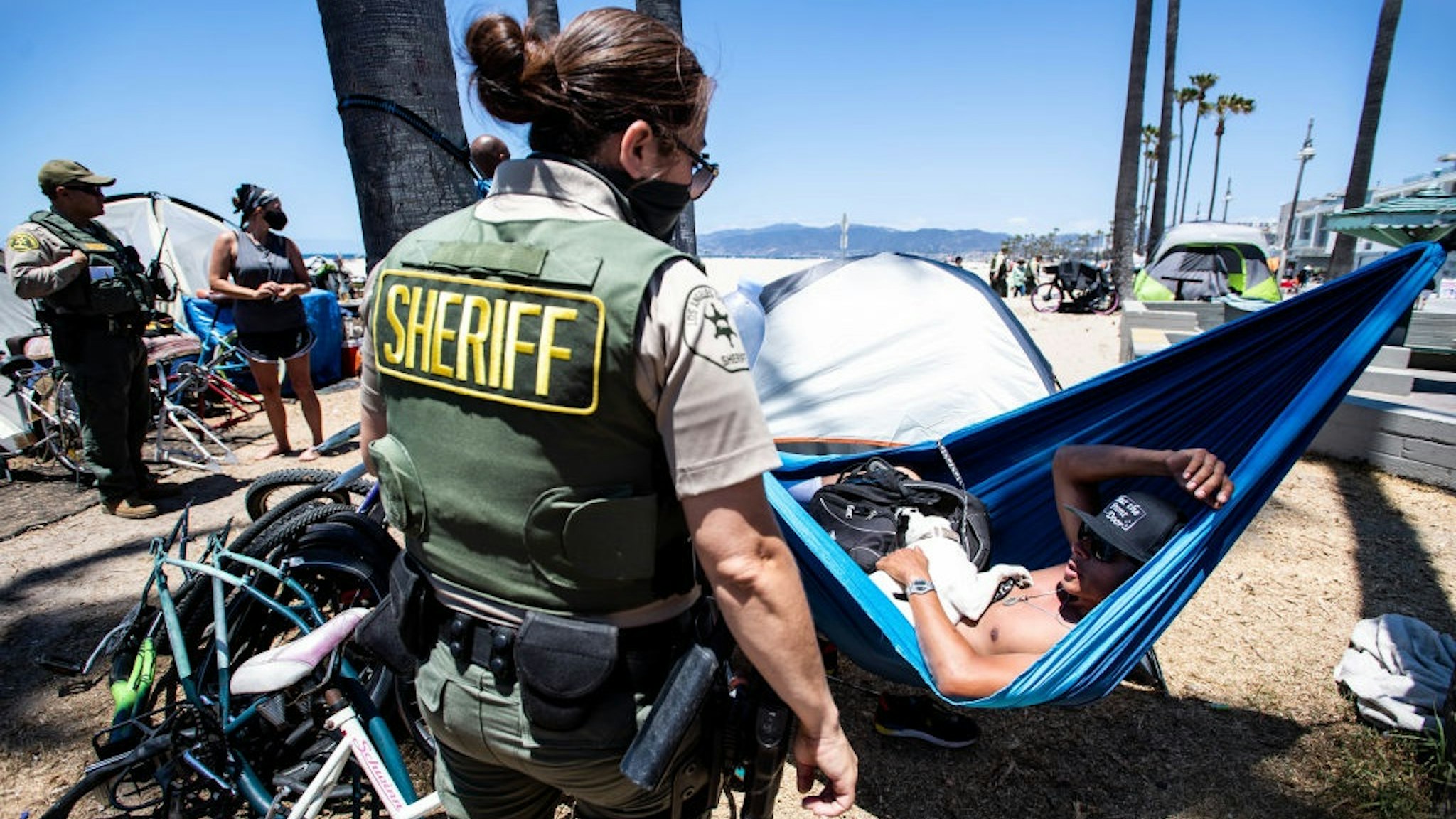 VENICE, CA - JUNE 08:Sheriff deputy Matson, of the Homeless Outreach Services Teams, encourages René Reyes, 28, on Tuesday, June 8, 2021 to leave the homeless encampment along the Venice Boardwalk where he has been living for the past three months after a divorce.