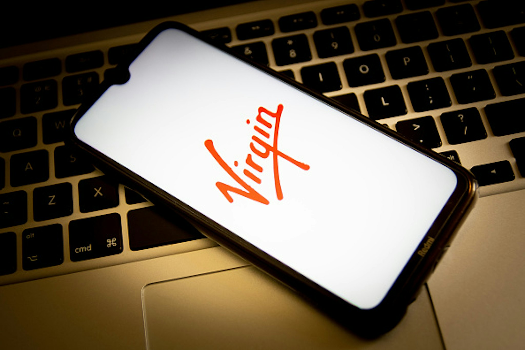 GREECE - 2021/04/23: In this photo illustration, a Virgin logo seen displayed on a smartphone screen with a computer keyboard in the background.