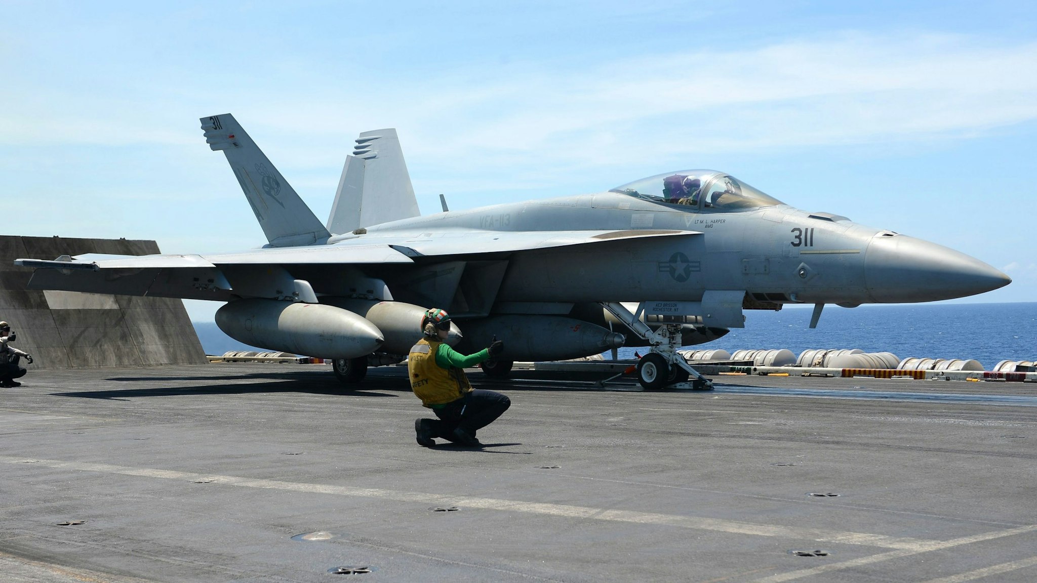 A sailor signals an FA-18 hornet fighter jet to take off during a routine training aboard US aircraft carrier Theodore Roosevelt in the South China sea on April 10, 2018. The carrier group Theodore Roosevelt is transiting through the South China sea on its way to the Philippines from Singapore after participating in Operations Inherent Resolve (OIR) and Operation Freedom's Sentinel (OFS) in Syria, Iraq and Afghanistan.