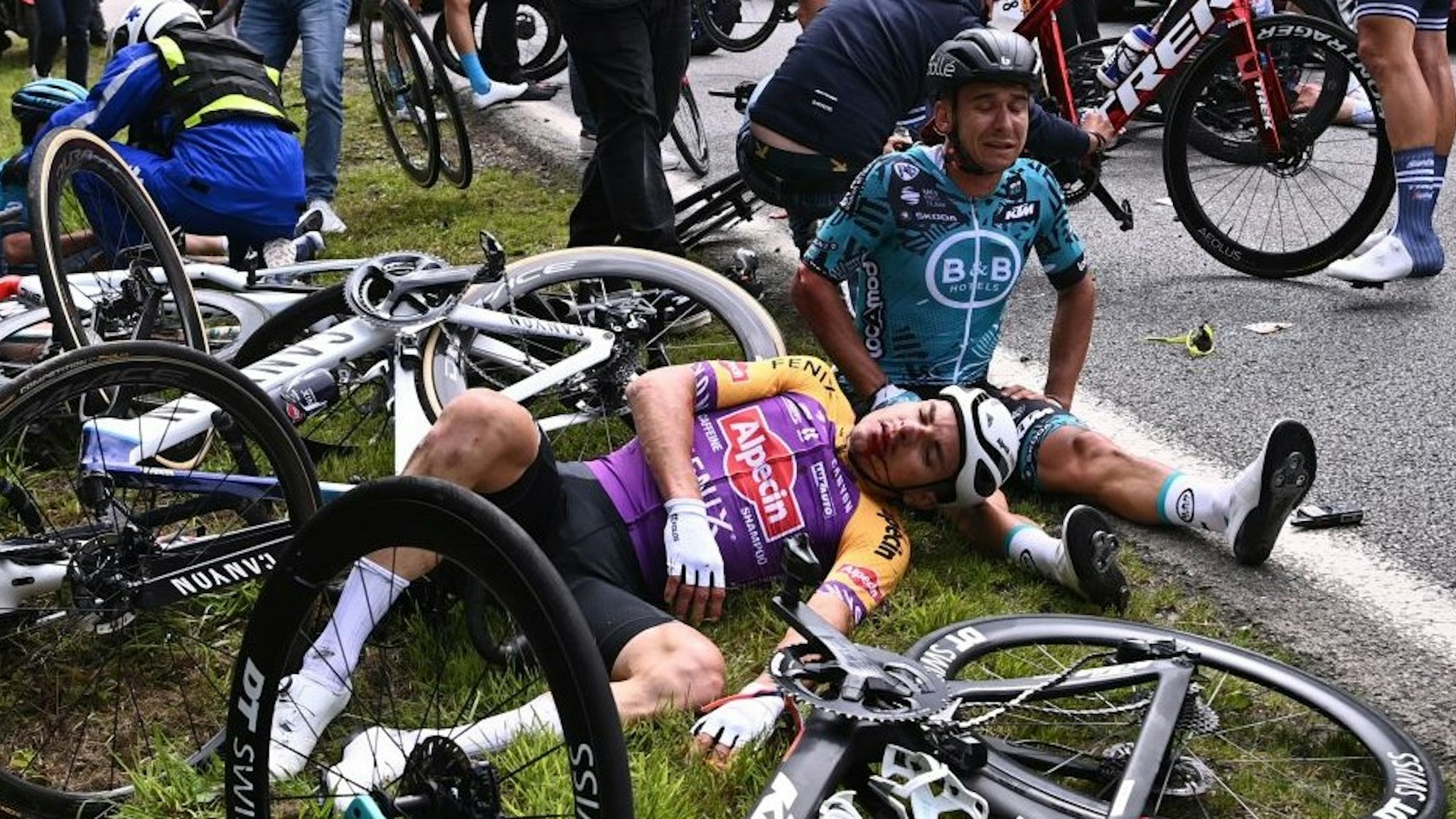 TOPSHOT - Team B&amp;B KTM's Bryan Coquard of France (R) and a Team Alpecin Fenix' rider lie on the ground after crashing during the 1st stage of the 108th edition of the Tour de France cycling race, 197 km between Brest and Landerneau, on June 26, 2021. (Photo by Anne-Christine POUJOULAT / various sources / AFP) (Photo by