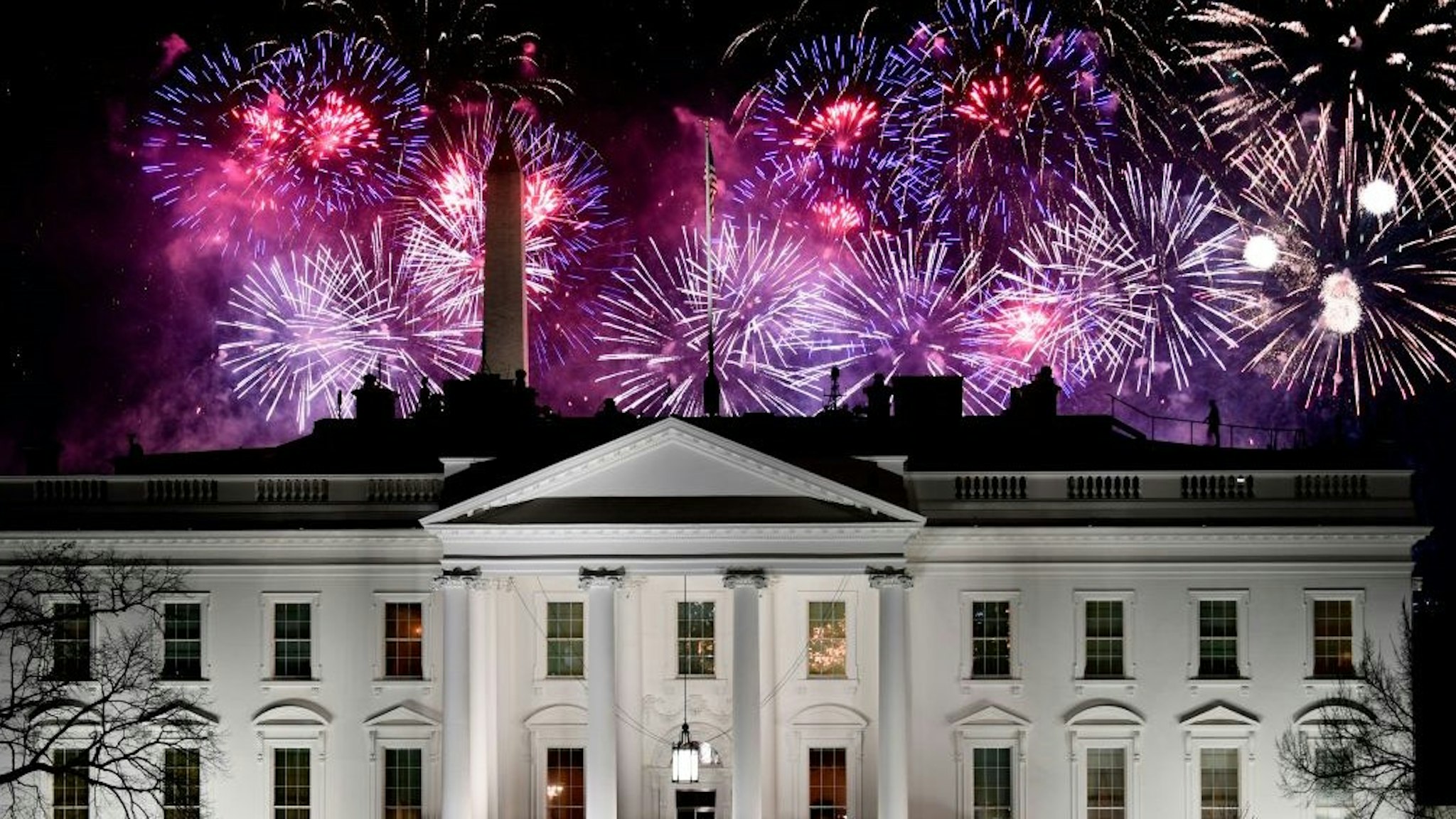 TOPSHOT - Fireworks are seen above the White House, with US Secret Service members watching from its roof, at the end of the Inauguration day for US President Joe Biden in Washington, DC, on January 20, 2021. (Photo by Patrick T. FALLON / AFP) (Photo by