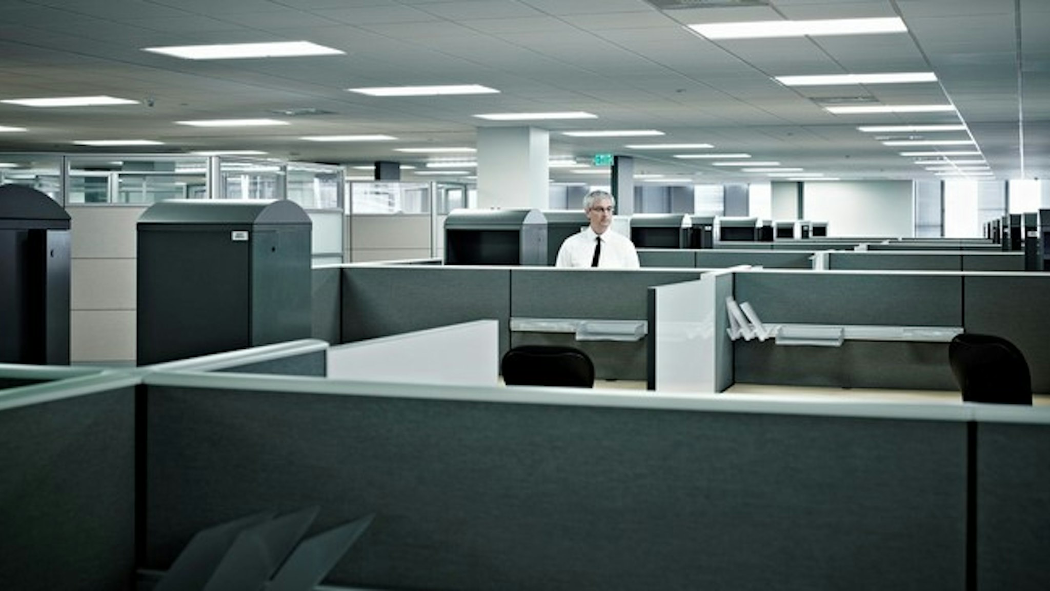 Mature businessman standing alone in cubicle