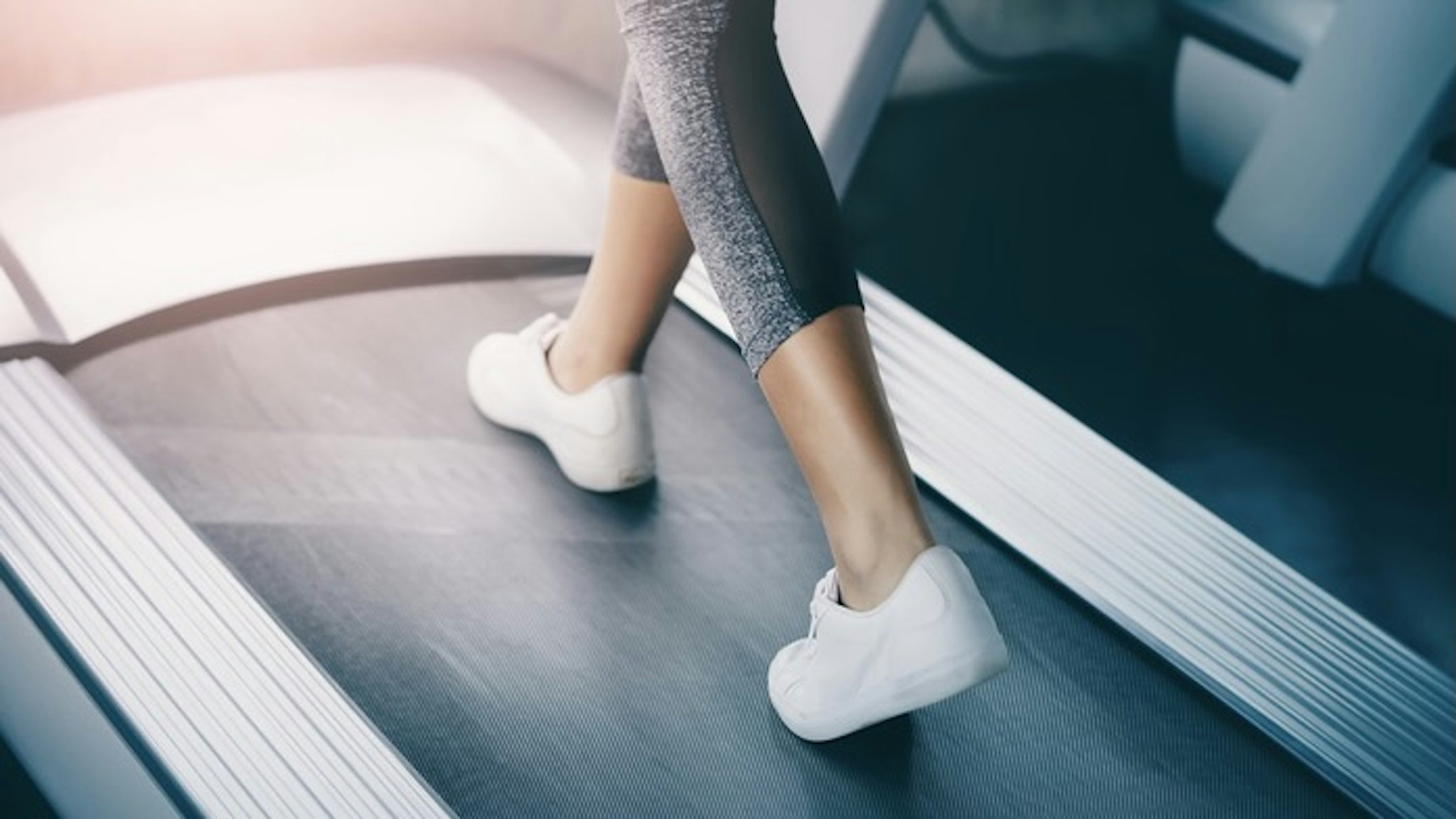 Indoor runner legs is walking slowly on the treadmill for light exercise closed up shot. - stock photo Indoor runner legs is walking slowly on the treadmill for light exercise closed up shot. junce via Getty Images