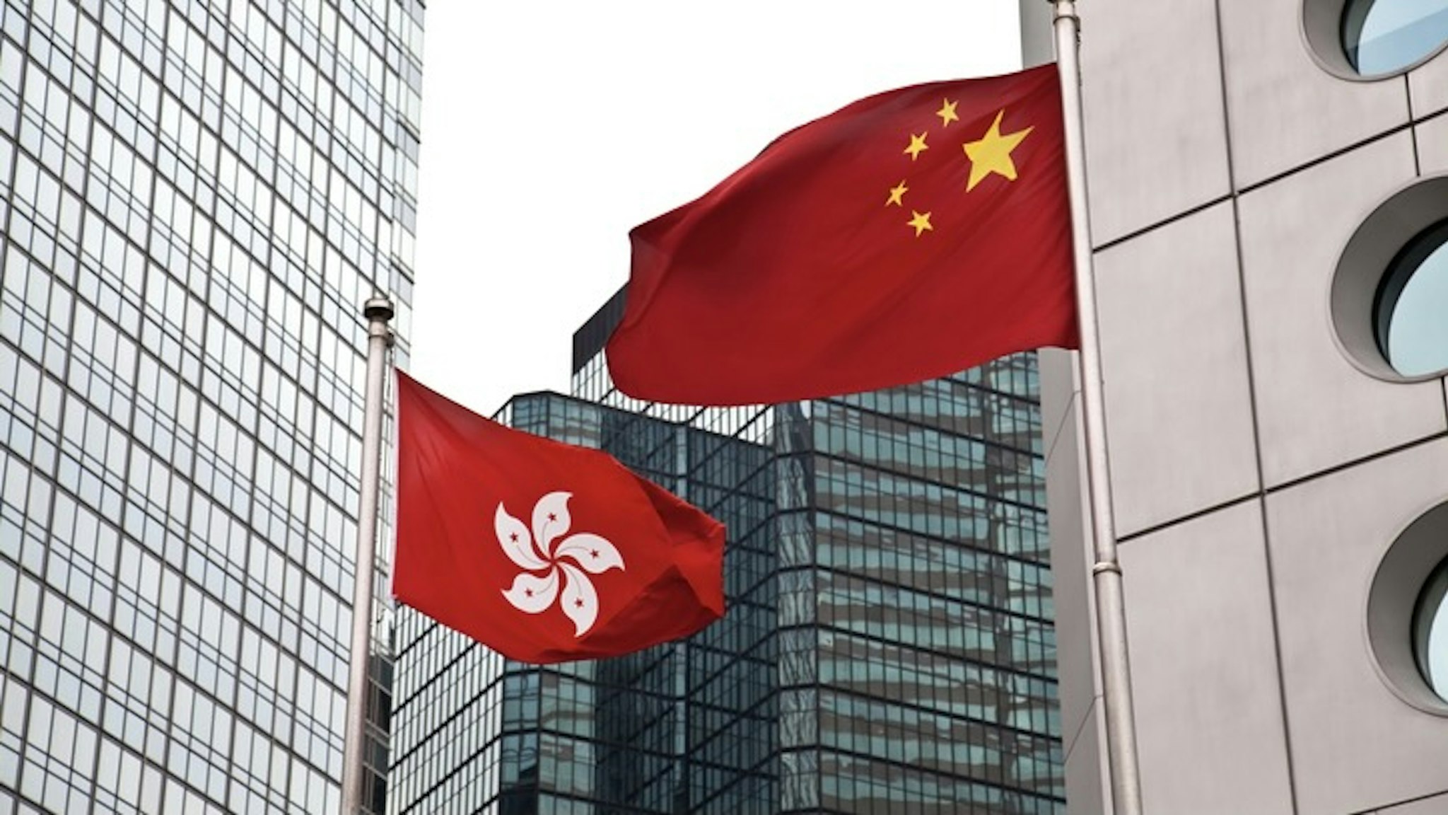Hong Kong and China - stock photo Hong Kong and China flags against commercial buildings ymgerman via Getty Images