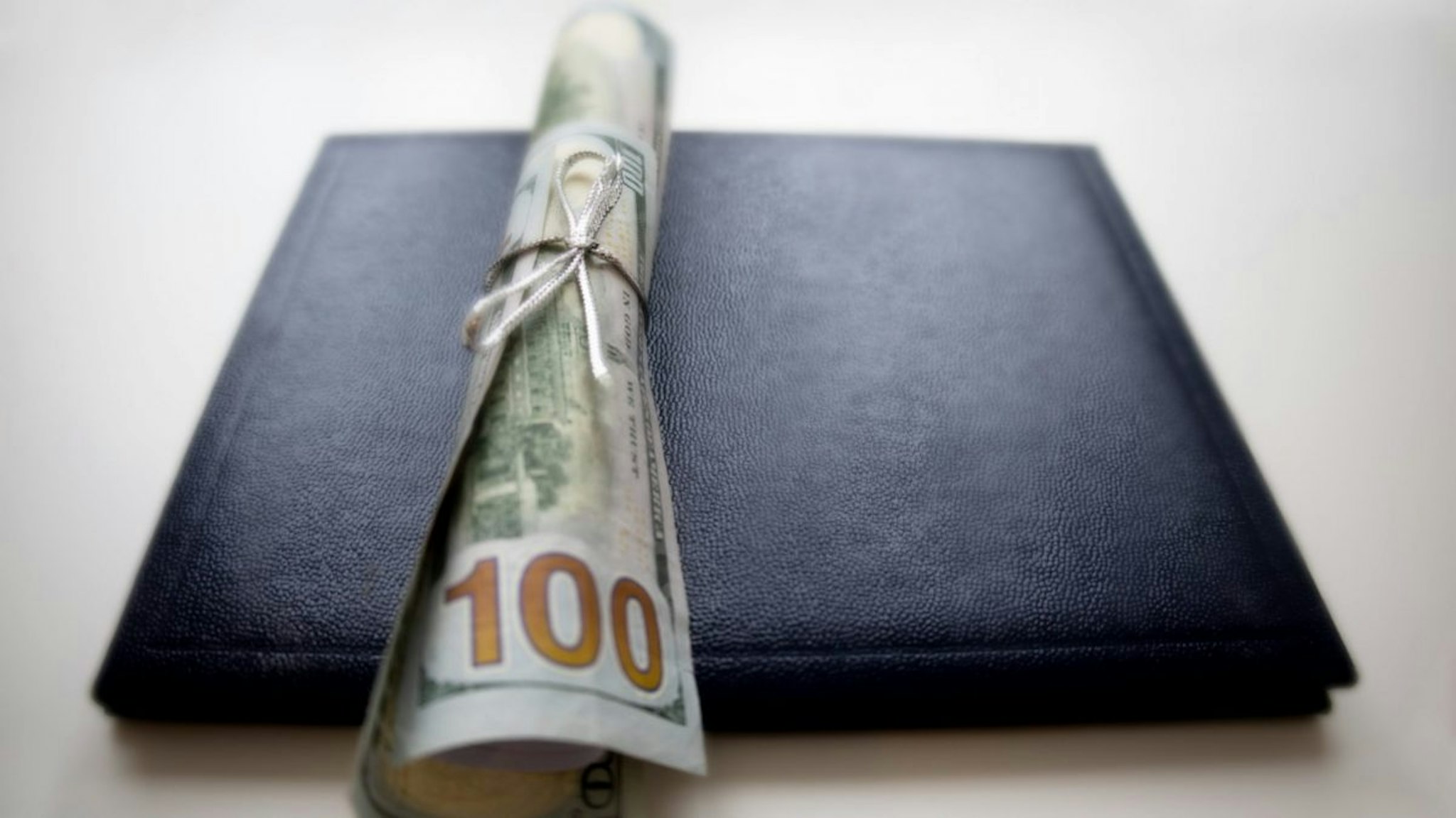 School diploma wrapped in $100 bills & traditional leather diploma binder - stock photo.