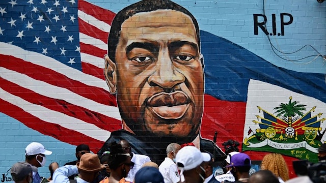 TOPSHOT - People gather at the unveiling of artist Kenny Altidor's memorial portrait of George Floyd - who died 25 May in Minneapolis with police officer Derek Chauvin kneeling on his neck for nearly nine minutes - painted on a storefront sidewall of CTown Supermarket on July 13, 2020 in Brooklyn, New York.