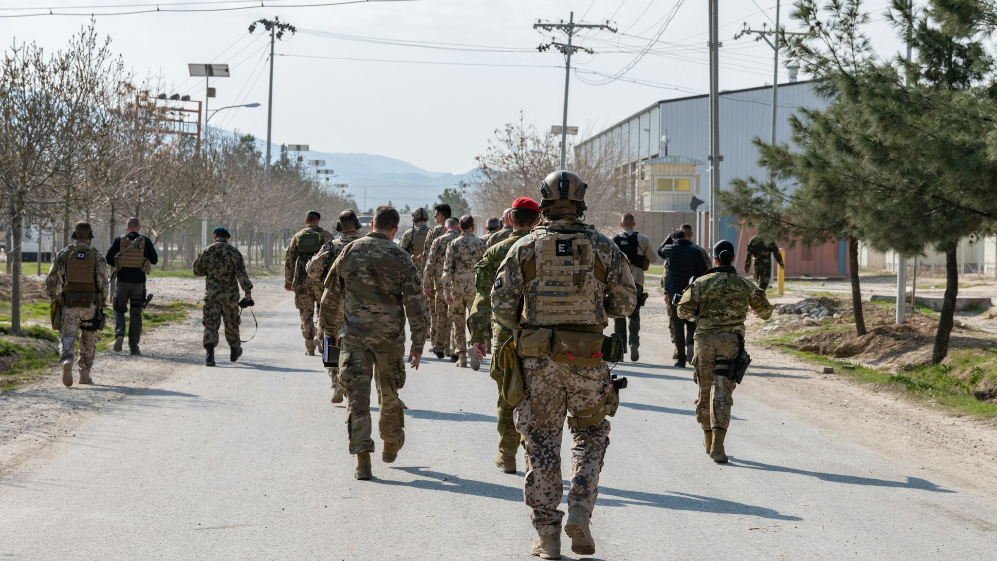 Rear View Of Army Soldiers Walking On Road In City - stock photo