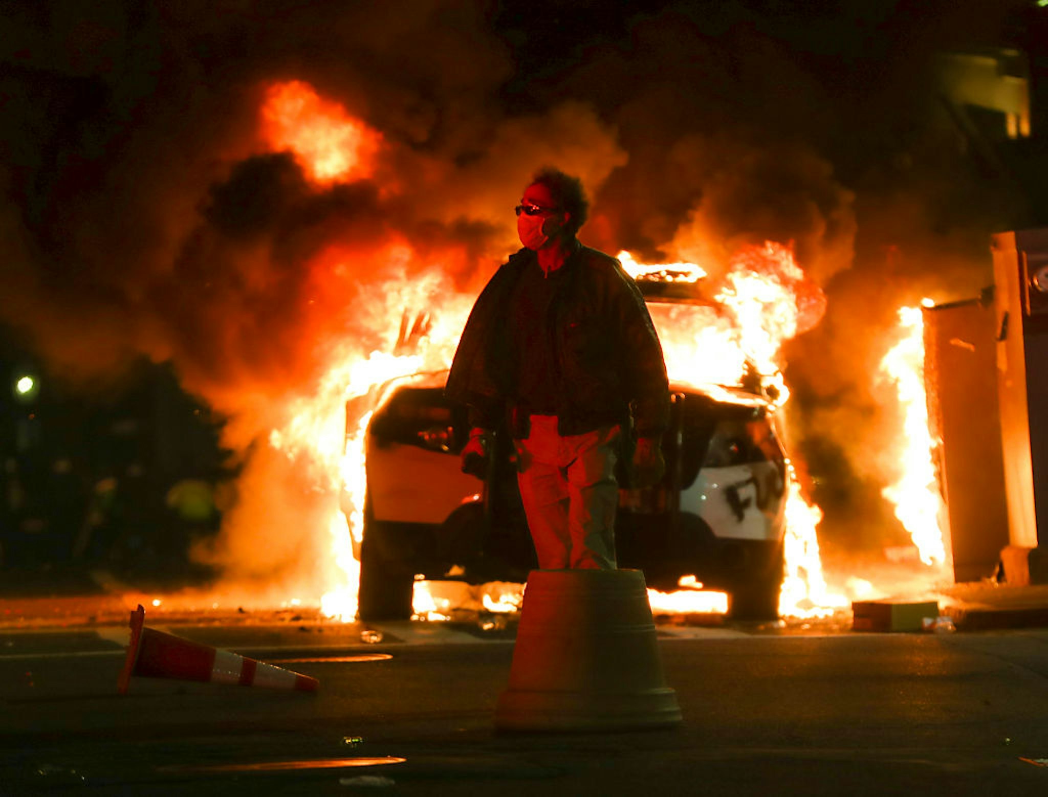 BOSTON, MA - JUNE 1: An unidentified man walks past a burning Boston Police car on Tremont Street in Boston on May 31, 2020 after a peaceful march from Dudley Square to the State House protesting the murder of George Lloyd by in Minneapolis by a police officer. (Photo by Matthew J. Lee/The Boston Globe via Getty Images)