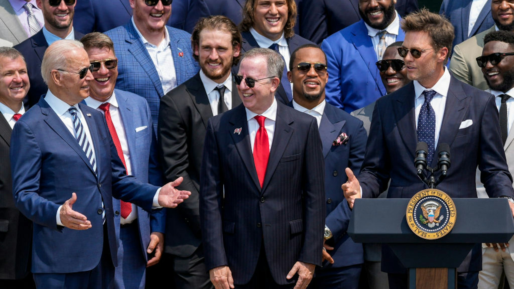 U.S. President Joe Biden laughs as quarterback Tom Brady jokes while speaking as the 2021 NFL Super Bowl champion Tampa Bay Buccaneers are welcomed to the South Lawn of the White House on July 20, 2021 in Washington, DC.