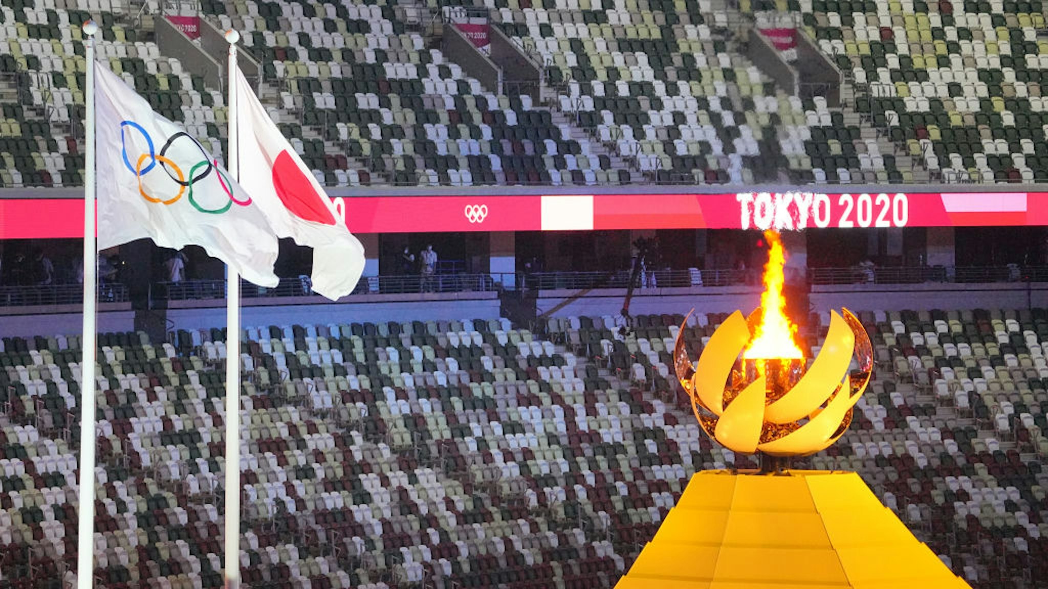 24 July 2021, Japan, Tokio: Olympia: Opening ceremony in the Olympic Stadium. The Olympic fire burns next to it the Olympic and Japanese flag. Photo: Michael Kappeler/dpa (Photo by Michael Kappeler/picture alliance via Getty Images)