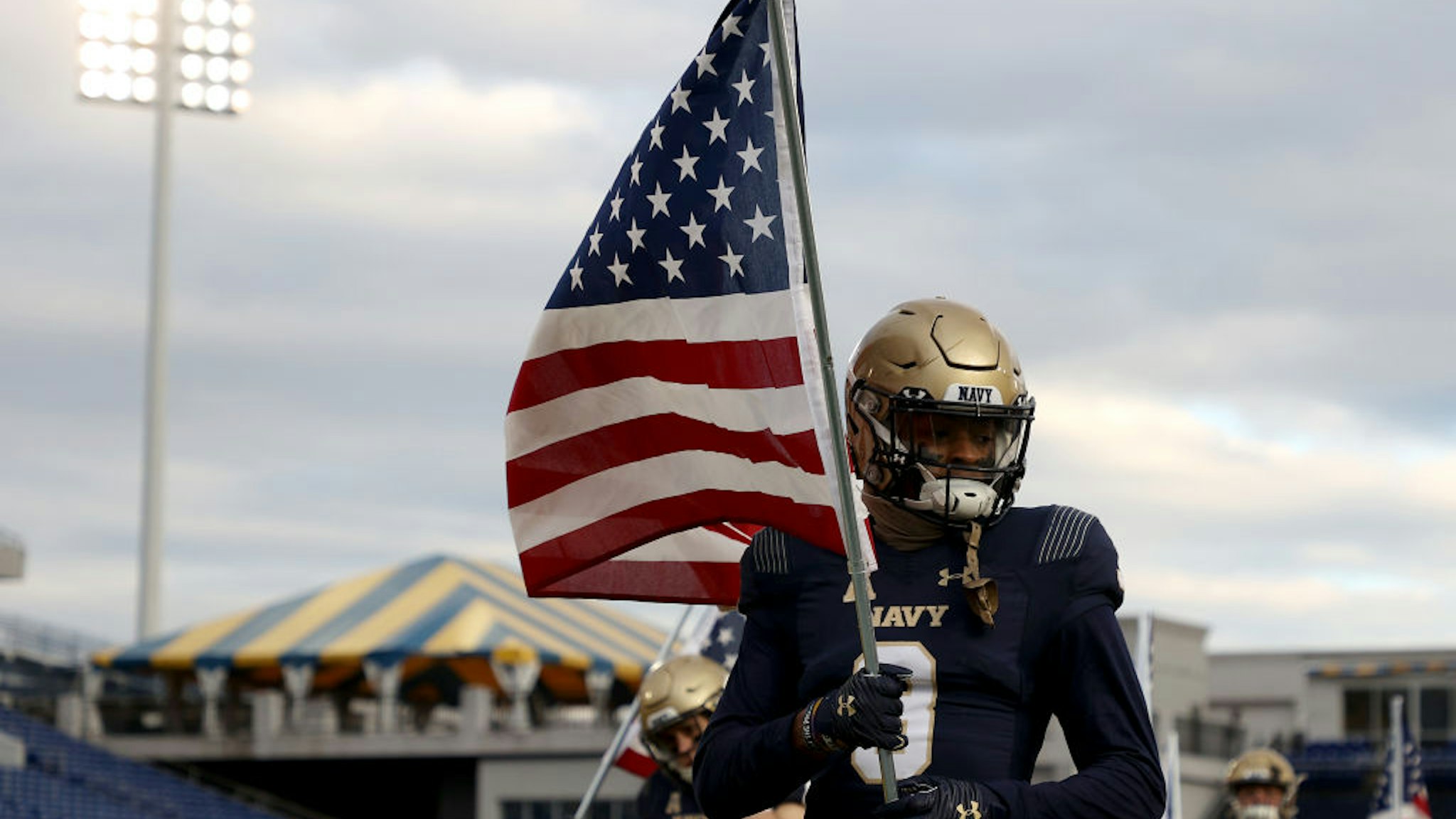 ANNAPOLIS, MARYLAND - DECEMBER 05: Cameron Kinley #3 of the Navy Midshipmen carries an American flag as the team takes the field against the Tulsa Golden Hurricane at Navy-Marine Corps Memorial Stadium on December 05, 2020 in Annapolis, Maryland. (Photo by Rob Carr/Getty Images)