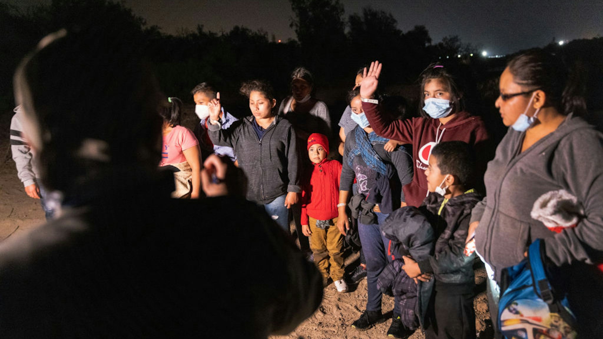 An unaccompanied minor raises her hand after a smuggler rowed her and other immigrants across the Rio Grande at the U.S.-Mexico border on April 9, 2021 in Roma, Texas.