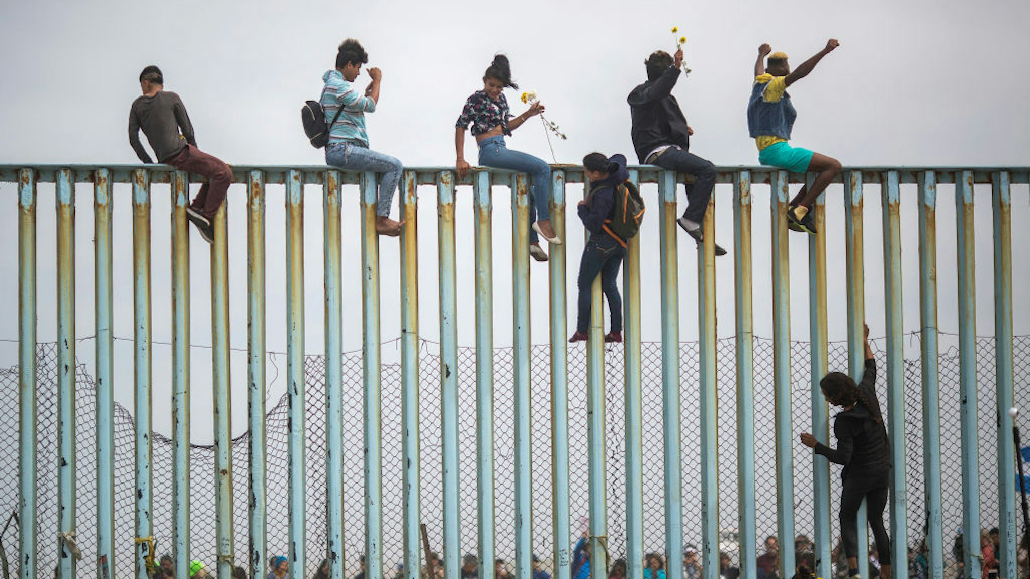TIJUANA, MEXICO - APRIL 29: People climb a section of border fence to look toward supporters in the U.S. as members of a caravan of Central American asylum seekers arrive to a rally on April 29, 2018 in Tijuana, Baja California Norte, Mexico. More than 300 immigrants, the remnants of a caravan of Central Americans that journeyed across Mexico to ask for asylum in the United States, have reached the border to apply for legal entry. (Photo by David McNew/Getty Images)