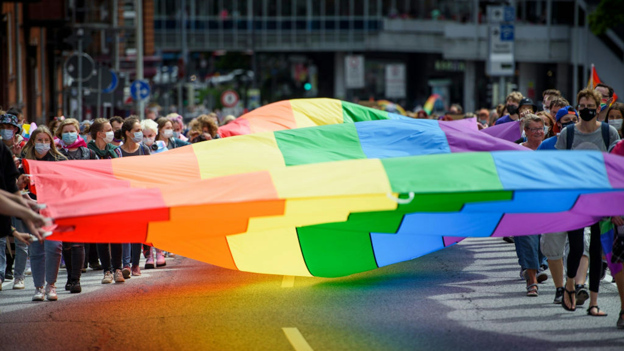 10 July 2021, Schleswig-Holstein, Kiel: Participants carry a huge rainbow flag through the city centre as part of the CSD (Christopher Street Day). The CSD takes place this year only as a demonstration. The traditional street party was cancelled by the organizers due to Corona