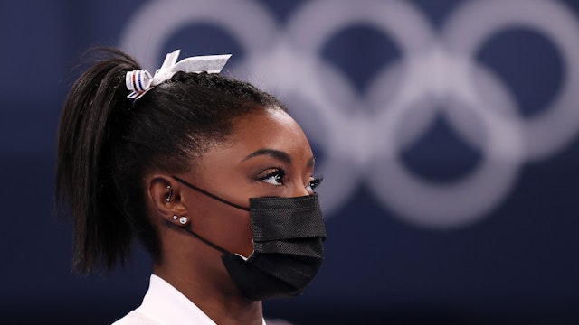 Simone Biles of Team United States watches her team perform on bars after pulling out of the competition after only competing on the vault during the Women's Team Final on day four on day four of the Tokyo 2020 Olympic Games at Ariake Gymnastics Centre on July 27, 2021 in Tokyo, Japan. (Photo by Laurence Griffiths/Getty Images)