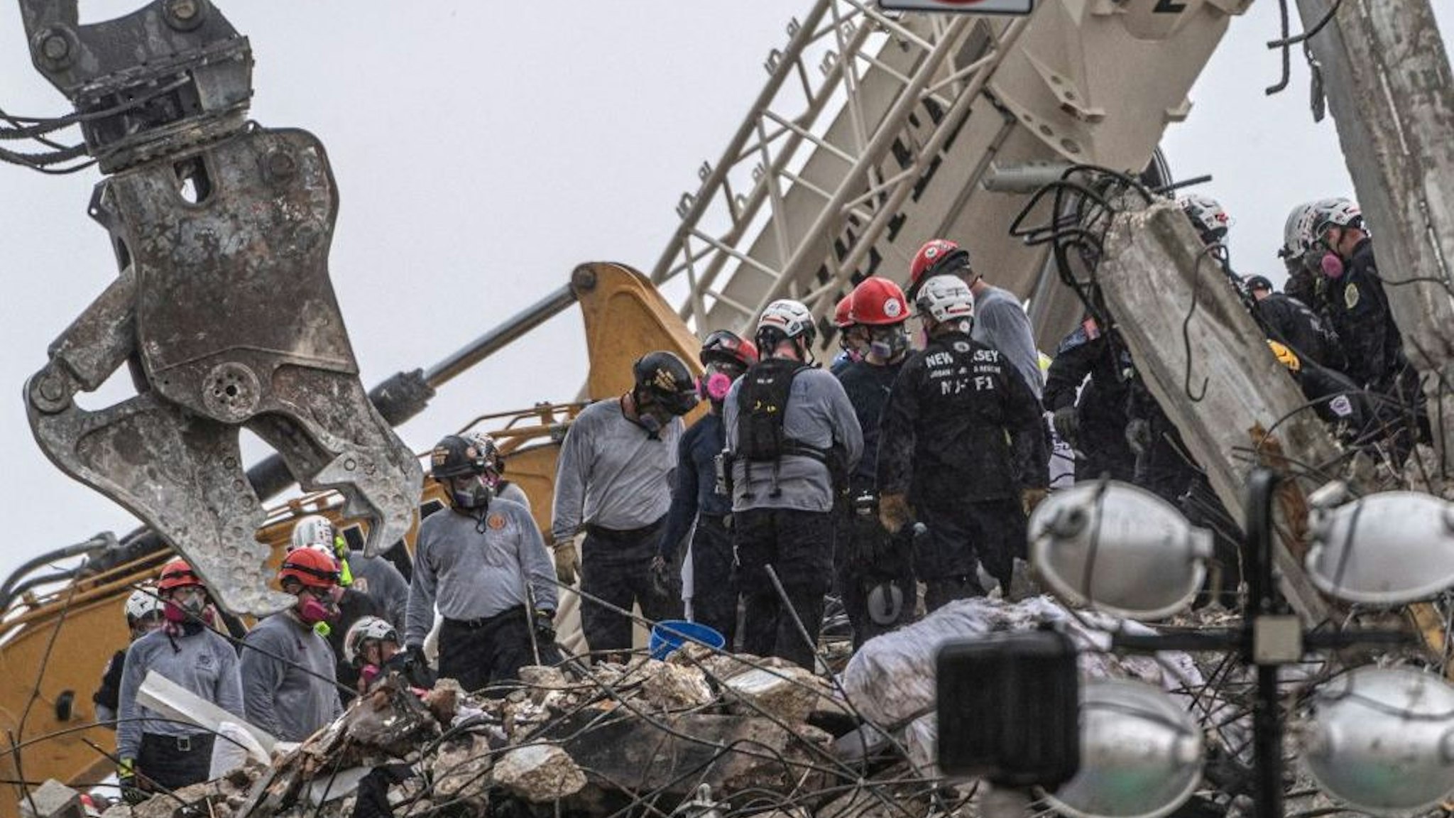 After a brief stop to demolish the standing debris, search and rescue personnel continue to work in the rain on the rubble pile of the 12-story Champlain Towers South condo that partially collapsed on July 5, 2021 in Surfside, Florida. - A controlled explosion brought down the unstable remains of the collapsed apartment block in Florida late on July 4 ahead of a threatening tropical storm as rescuers prepare to resume searching for victims.