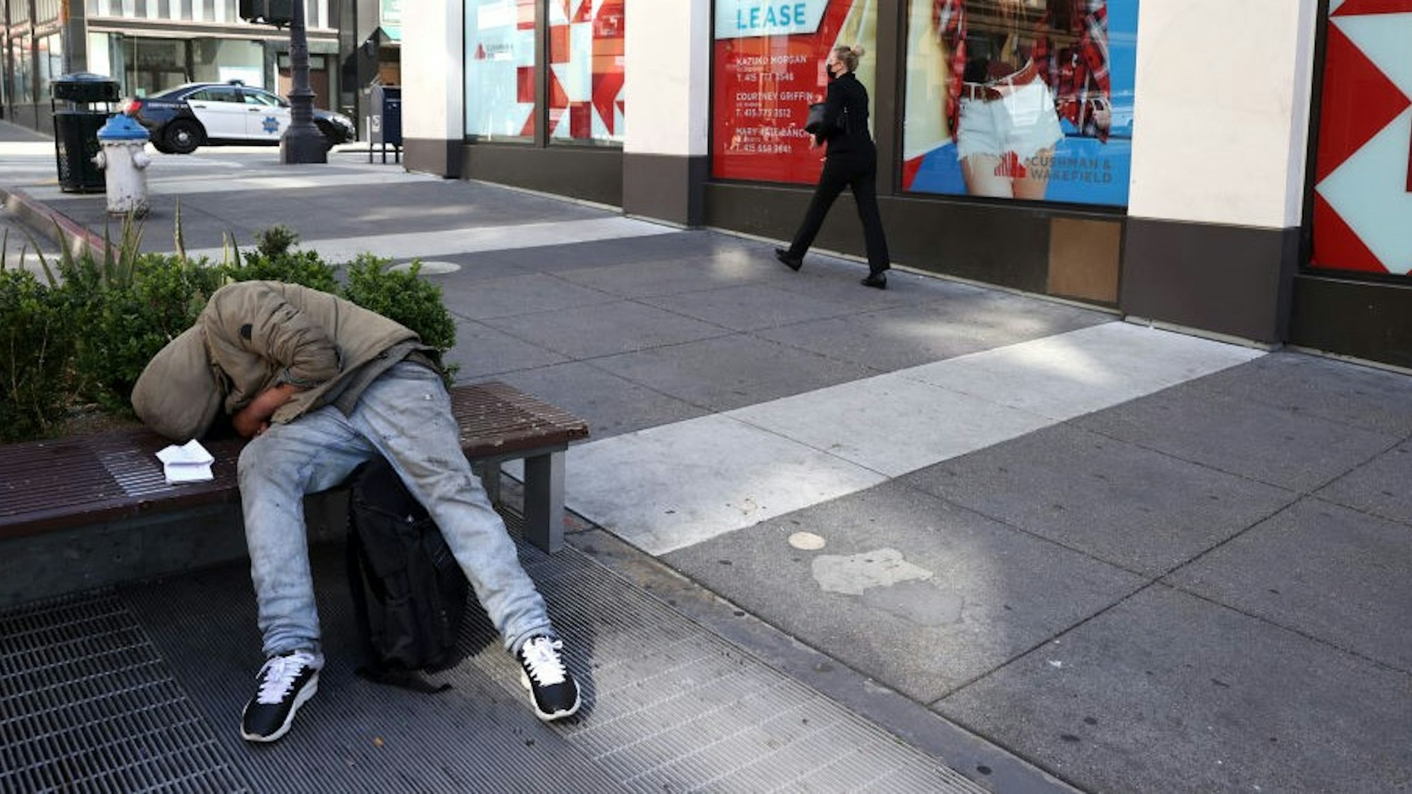 SAN FRANCISCO, CALIFORNIA - APRIL 16: A homeless person sleeps on a bench in front of closed retail stores on April 16, 2021 in San Francisco, California. As San Francisco begins to slowly reopen a year after the city went into lockdown due to theCOVID-19 pandemic, many of the city's businesses have shut their doors forever. San Francisco mayor London Breed is asking San Franciscans to patronize local businesses for the next 30 days as she pushes to prioritize small businesses. (Photo by