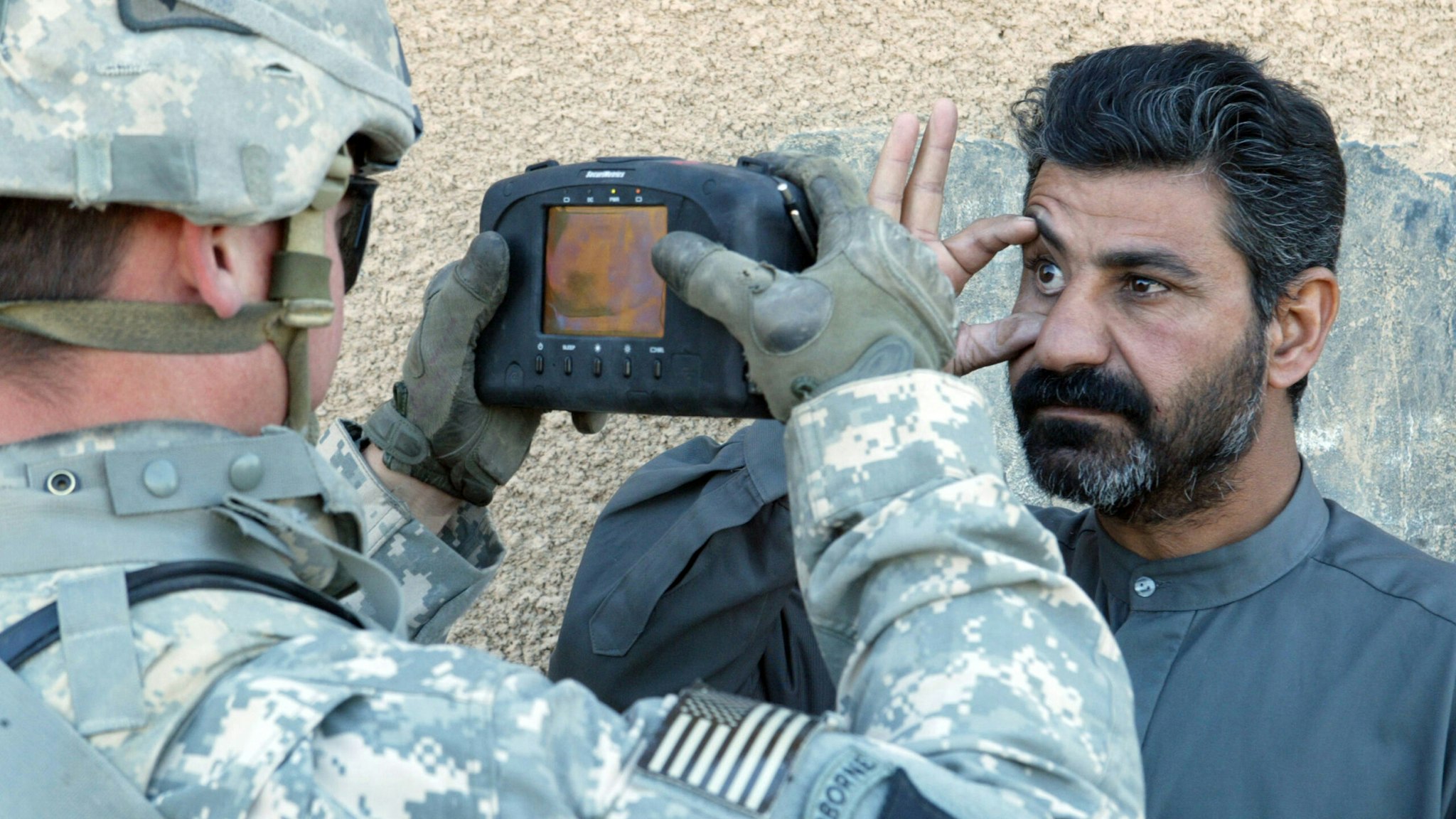 An iraqi citizen has his eye scanned by a US soldier with the 1st Squadron, 33rd Cavalry Regiment, in Hoy Al Askariah a small town south of Baghdad. The device being used is the HIIDE or Hand-held Interagency Identity Detection Equipment system, a biometric identification database with the which soldier can quickly input and access the name, age, address, religious sect, birthplace, fingerprints, retinal information, and facial photograph of any individual who has already been entered into the system. | Location: Hoy Al Askariah, Iraq.