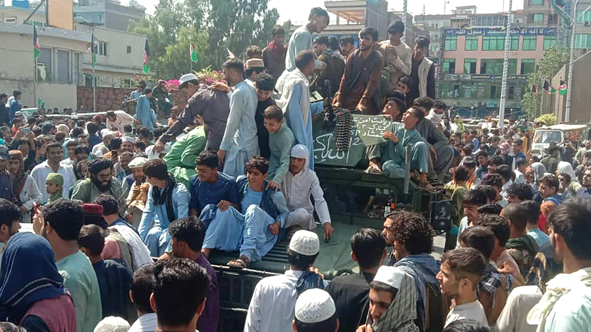 TOPSHOT - Taliban fighters and local people sit on an Afghan National Army (ANA) Humvee vehicle on a street in Jalalabad province on August 15, 2021.