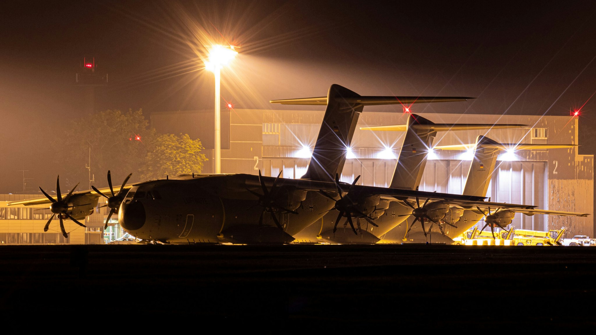 15 August 2021, Lower Saxony, Wunstorf: Airbus A400M transport aircraft of the German Air Force stand behind a fence at the Wunstorf air base in the Hanover region in the evening. In view of the rapid advance of the Taliban in Afghanistan, the Bundeswehr plans to begin evacuating German citizens and local Afghan forces from Kabul on Monday (16.08.2021).