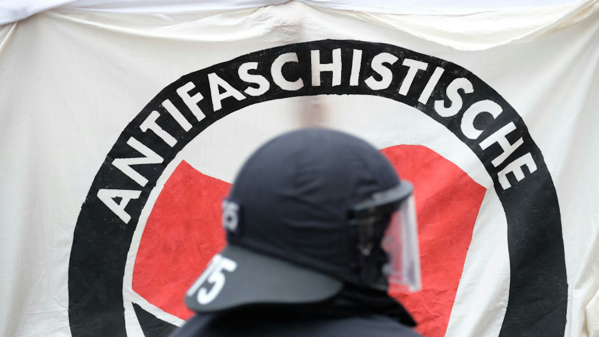 07 August 2021, Thuringia, Weimar: A policeman stands in front of an Antifa banner during a left-wing demonstration. Photo: Sebastian Willnow/dpa-Zentralbild/dpa