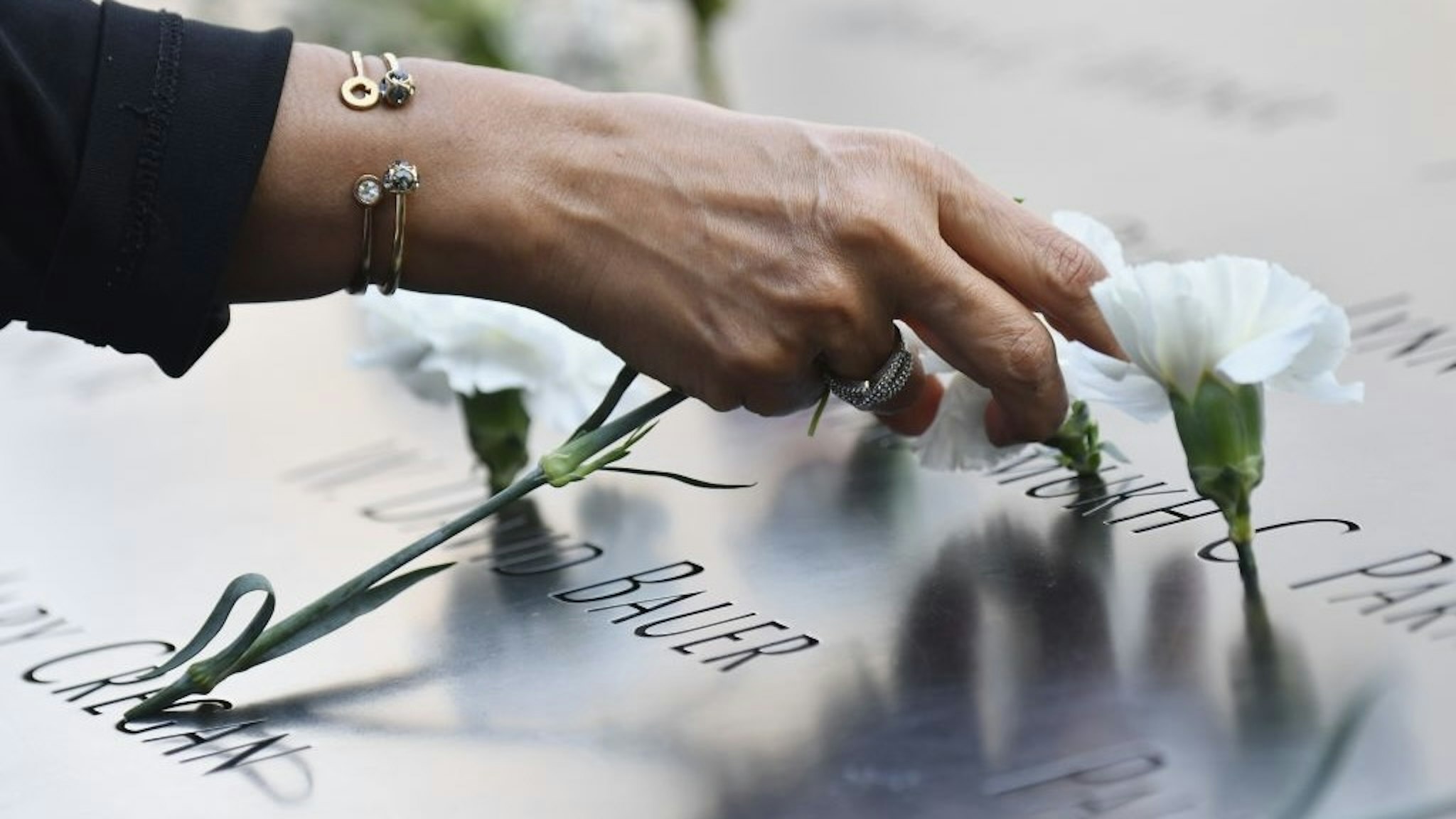US-ATTACKS-9/11-ANNIVERSARY A mourner places flowers at the 9/11 Memorial & Museum in New York on September 11, 2020, as the US commemorates the 19th anniversary of the 9/11 attacks. (Photo by Angela Weiss / AFP) (Photo by ANGELA WEISS/AFP via Getty Images) ANGELA WEISS / Contributor via Getty Images