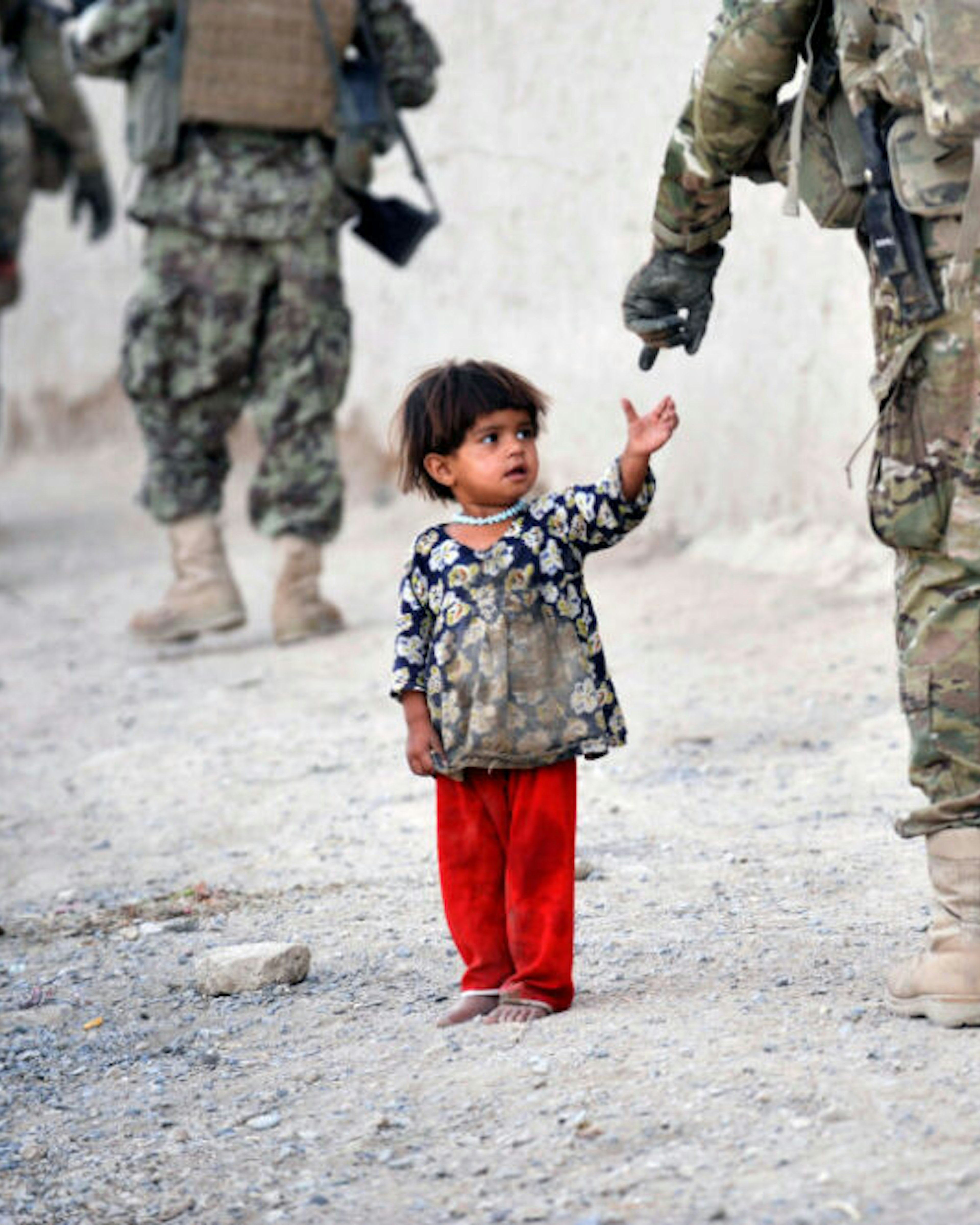 An Afghan girl greets a joint patrol of US troops from the Charlie Company, 2-87 Infantry, 3rd Brigade Combat Team and Afghan National Army soldiers at Kandalay village in the southern Afghan province of Kandahar on August 8, 2011 while US troops launched missile attacks on Taliban targets in nearby Kelawai village killing at least three and capturing two insurgents. US forces push their counterinsurgency efforts to battle for the hearts and minds of the local population.