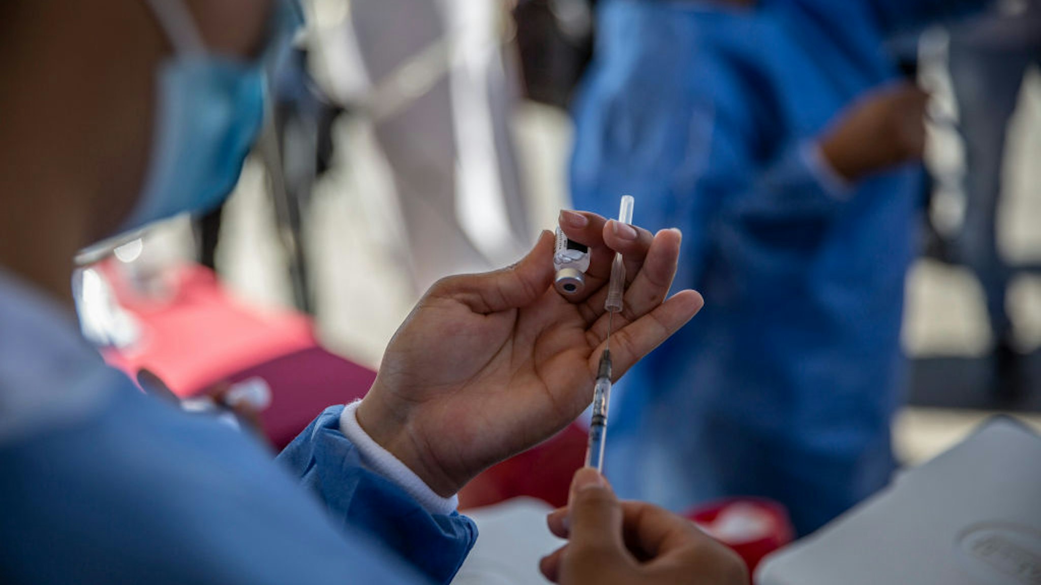 3 August 2021, Mexico, Tijuana: A health worker prepares a Corona vaccination as part of a vaccination drive for migrants outside the El Chaparral border crossing. The action was organized by the health department of the Mexican state of Baja California. More than 500 migrants living in an improvised camp at the border crossing were to receive the Corona vaccine from Pfizer-Biontech. Photo: Stringer/dpa (Photo by Stringer/picture alliance via Getty Images)