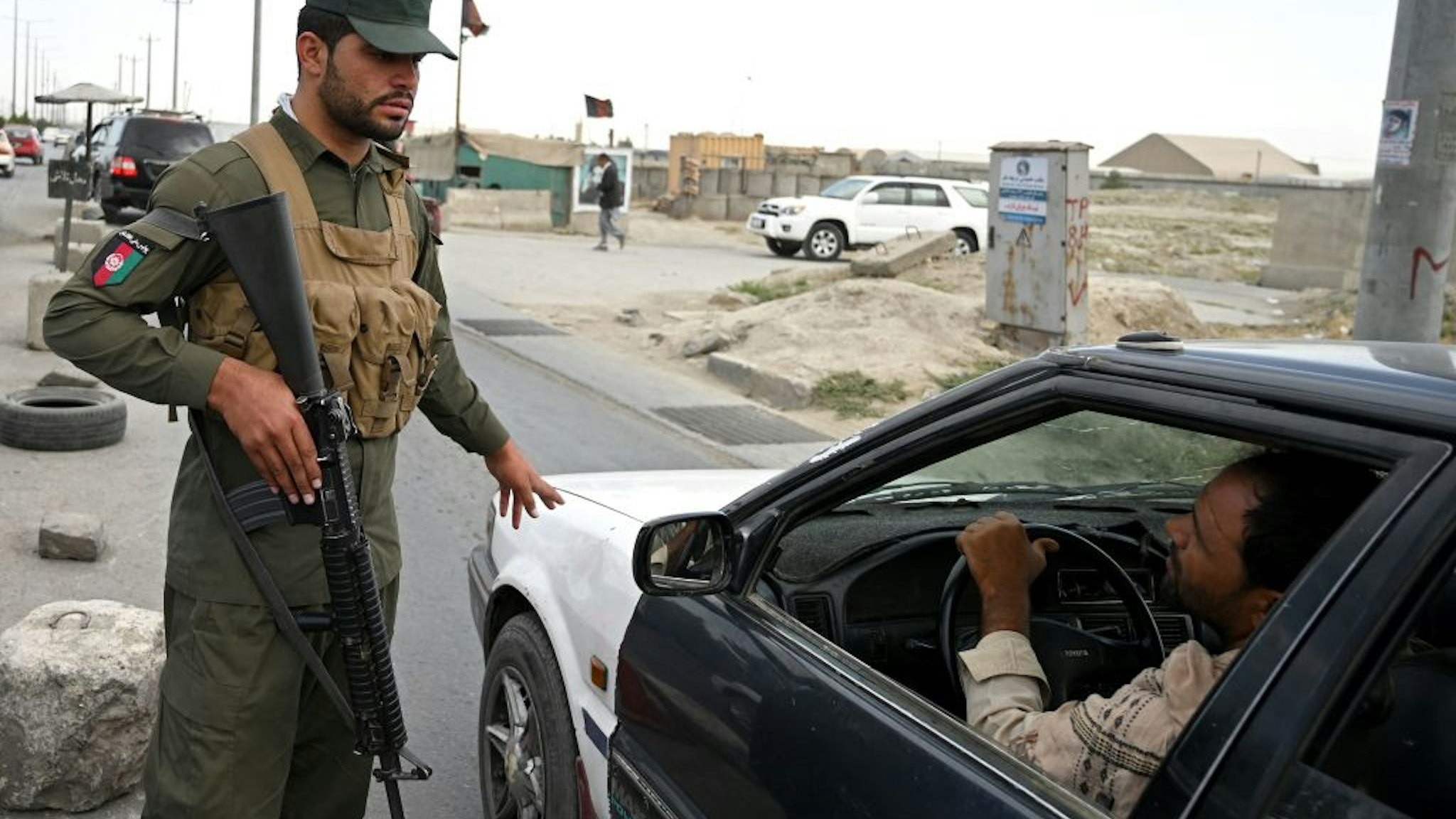 An Afghan policeman speaks to a commuter in car at a checkpoint along the road in Kabul on August 14, 2021. (Photo by WAKIL KOHSAR / AFP) (Photo by WAKIL KOHSAR/AFP via Getty Images)