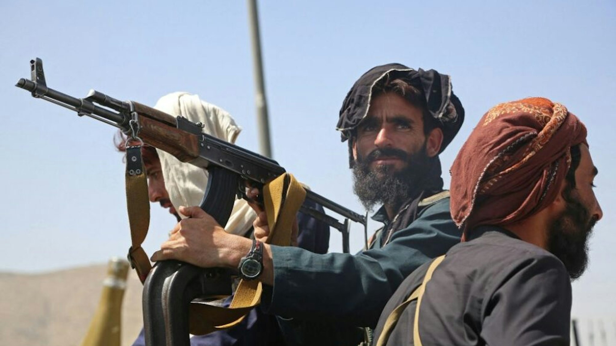 TOPSHOT - Taliban fighters stand guard in a vehicle along the roadside in Kabul on August 16, 2021, after a stunningly swift end to Afghanistan's 20-year war, as thousands of people mobbed the city's airport trying to flee the group's feared hardline brand of Islamist rule.