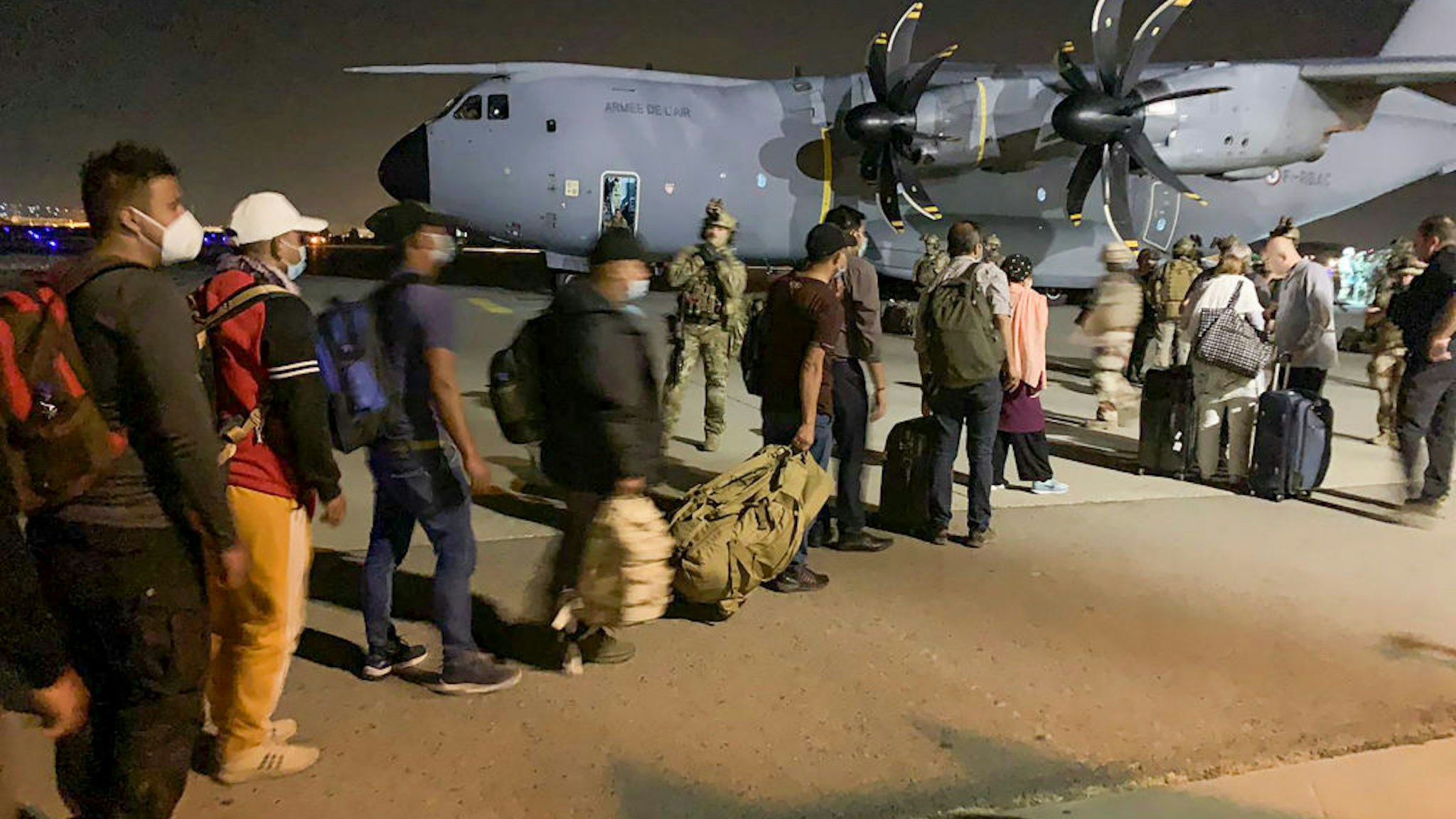 TOPSHOT - People line up to board a French military transport plane at the Kabul airport on August 17, 2021, for evacuation from Afghanistan after the Taliban's stunning military takeover of the country. (Photo by STR / AFP) (Photo by STR/AFP via Getty Images)