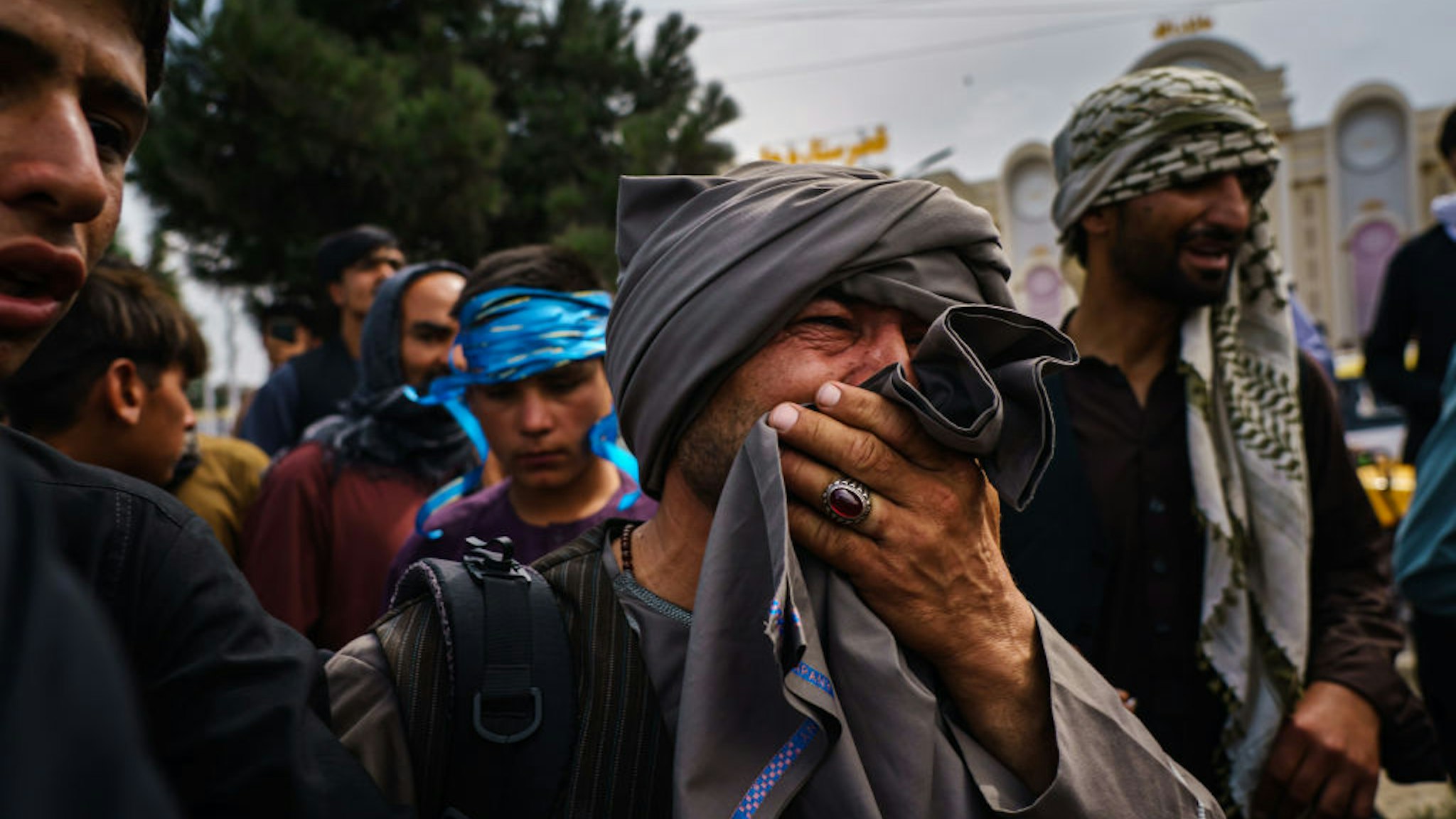KABUL, AFGHANISTAN -- AUGUST 17, 2021: A man cries as he watches fellow Afghans get wounded after Taliban fighters use guns fire, whips, sticks and sharp objects to maintain crowd control over thousands of Afghans who continue to wait outside the Kabul Airport for a way out, on airport road in Kabul, Afghanistan, Tuesday, Aug. 17, 2021. At least half dozen were wounded, within the hour of violent escalation, including a woman and her child. (MARCUS YAM / LOS ANGELES TIMES)